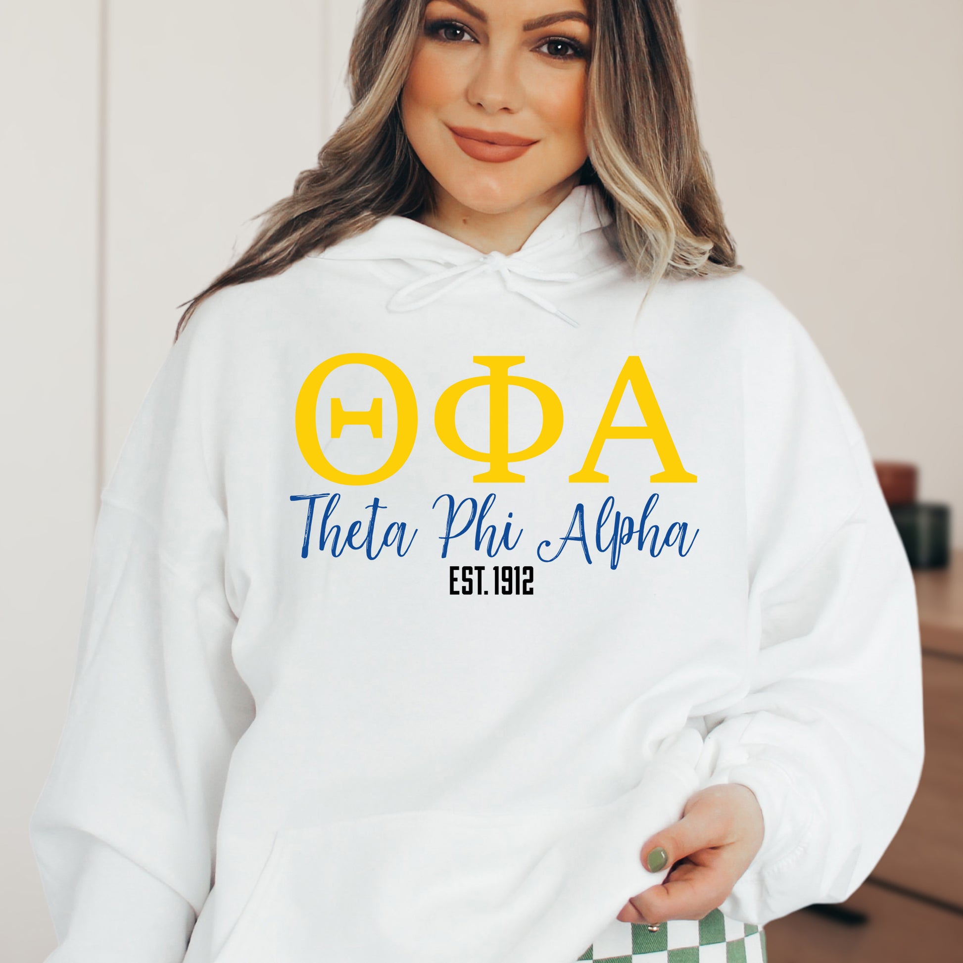 a woman wearing a white hoodie with greek letters