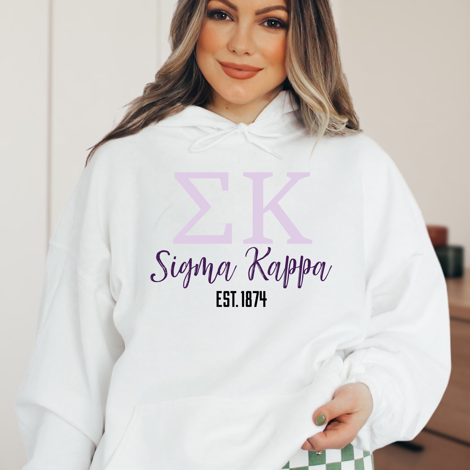 a woman wearing a white hoodie with the letter k on it