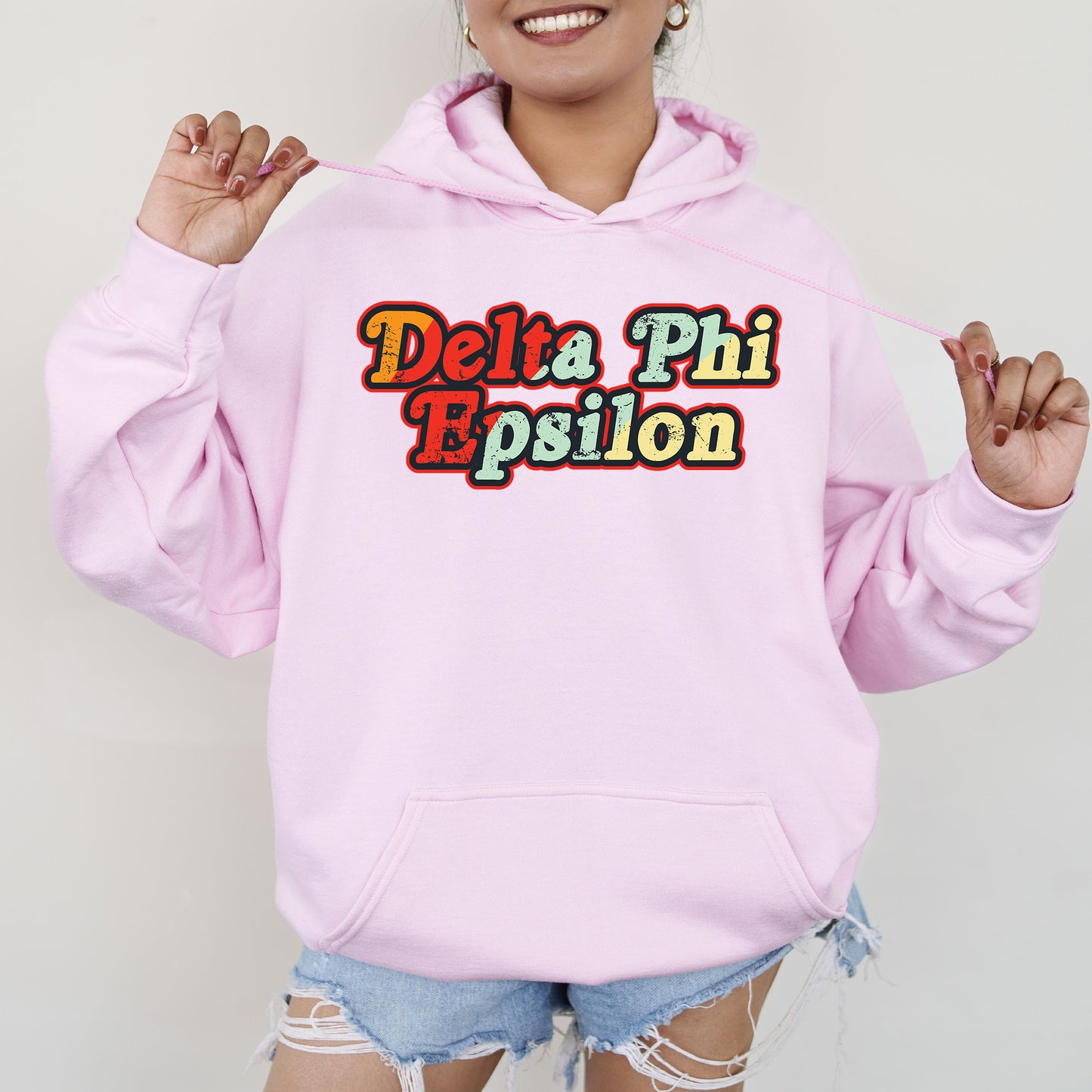 a woman wearing a pink hoodie that says delta phi espion