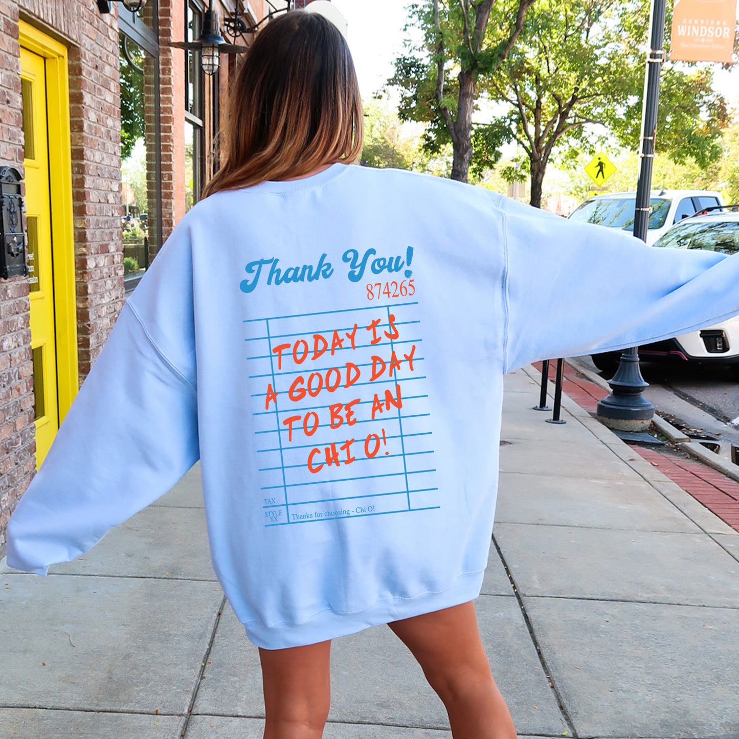 a woman walking down a sidewalk wearing a blue sweatshirt