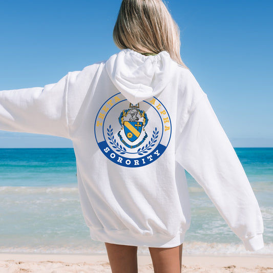 a woman standing on a beach wearing a white hoodie