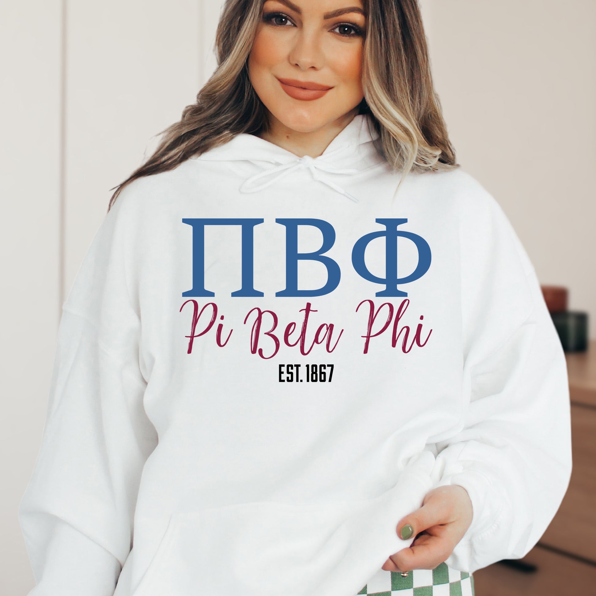 a woman wearing a white hoodie with greek letters