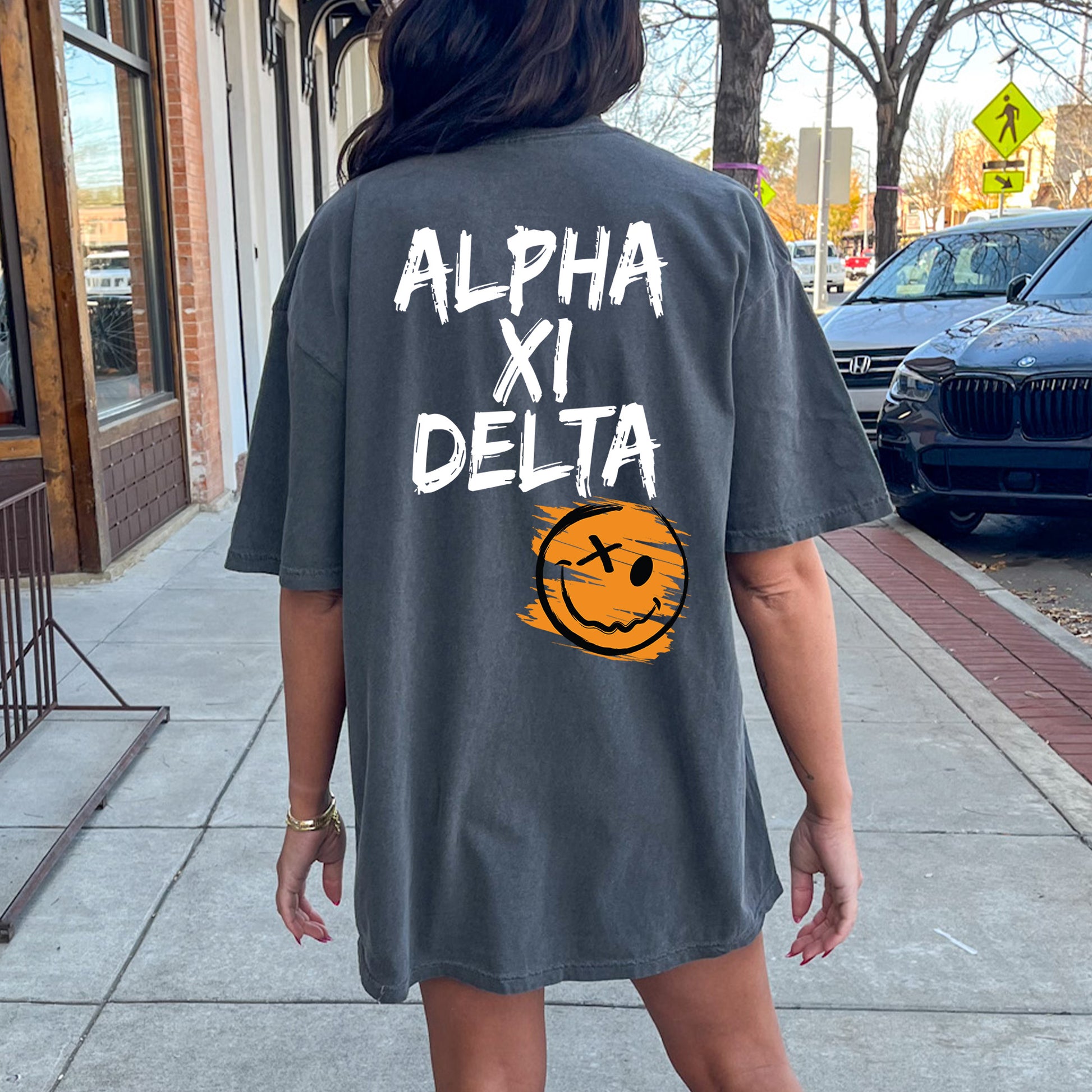 a woman walking down a sidewalk wearing a shirt that says alphi xi delta