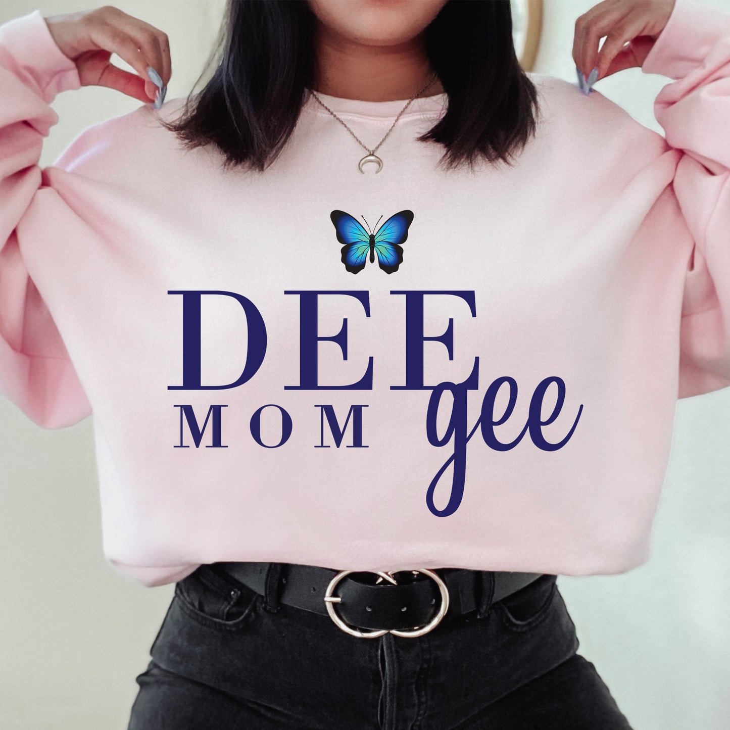 a woman holding a pink sweatshirt with a butterfly on it