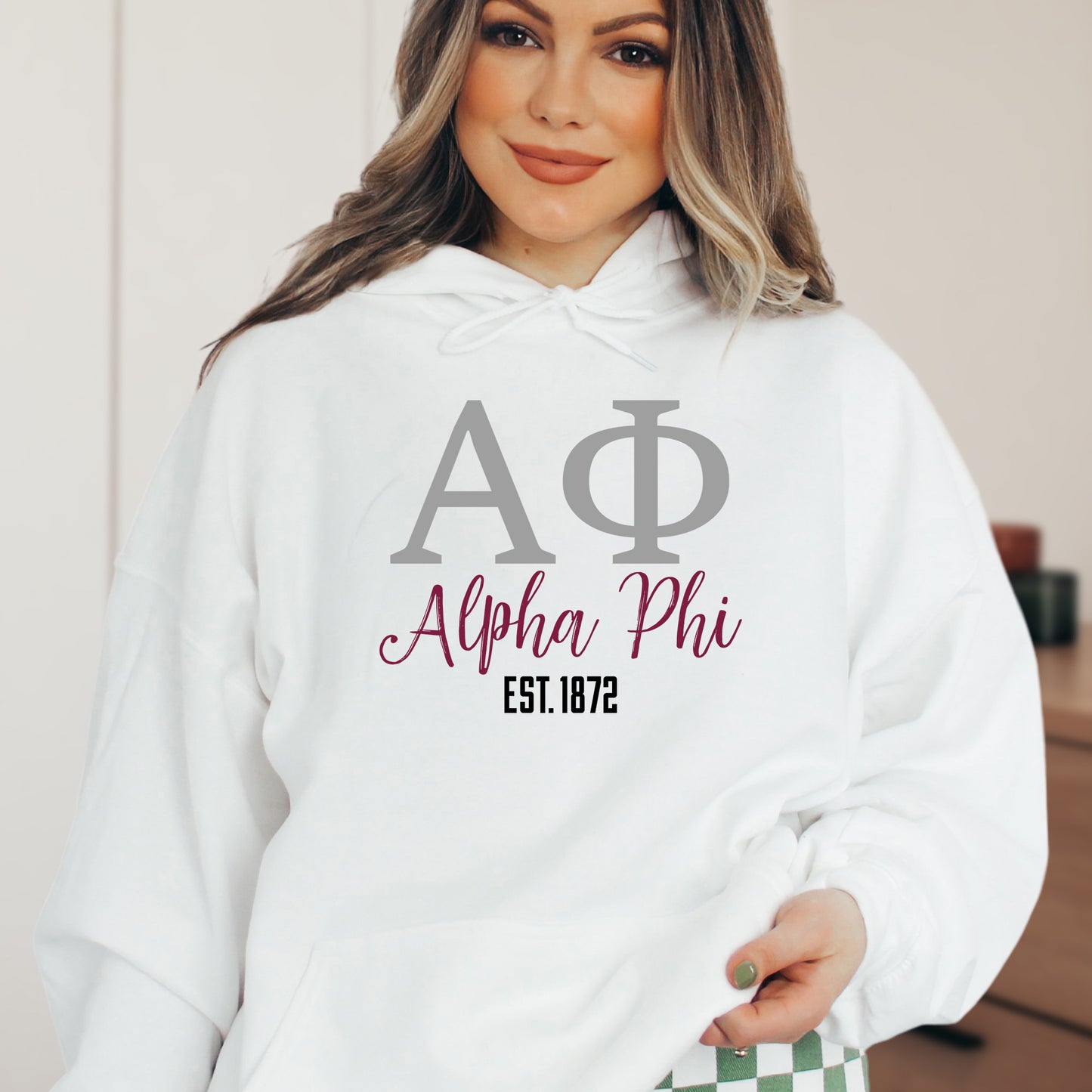 a woman wearing a white hoodie with a phi phi on it