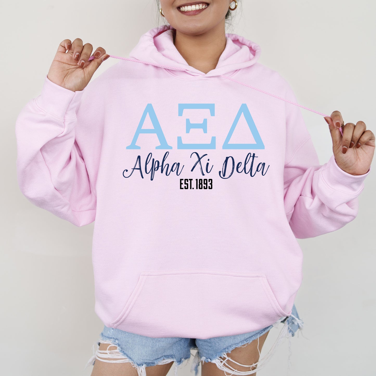 a woman wearing a pink hoodie and ripped shorts
