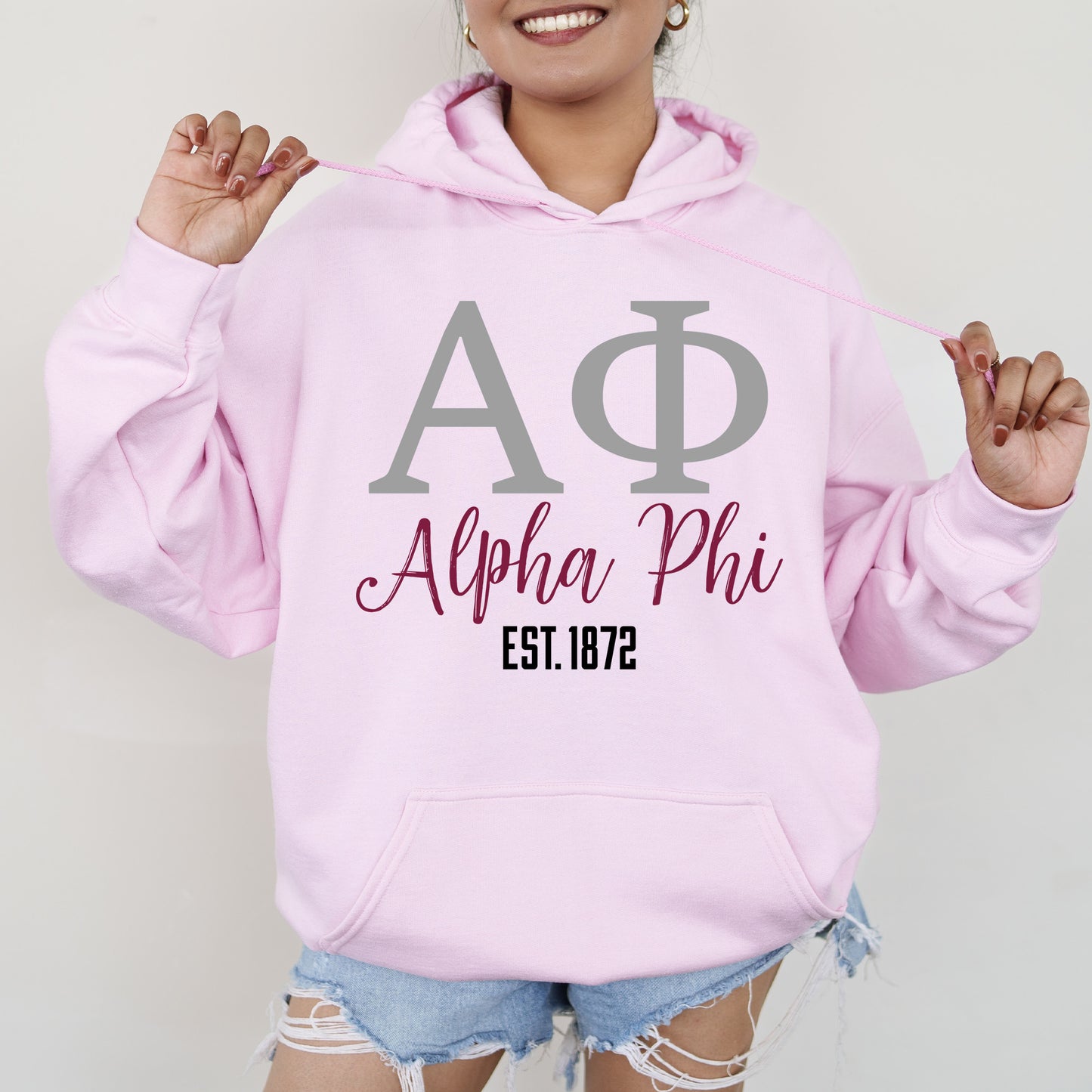a woman wearing a pink hoodie with a phi phi on it