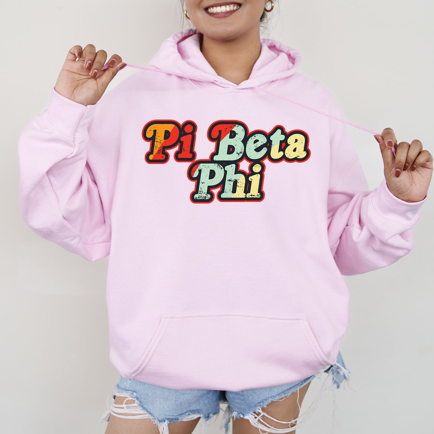 a woman wearing a pink hoodie that says pi beta pi