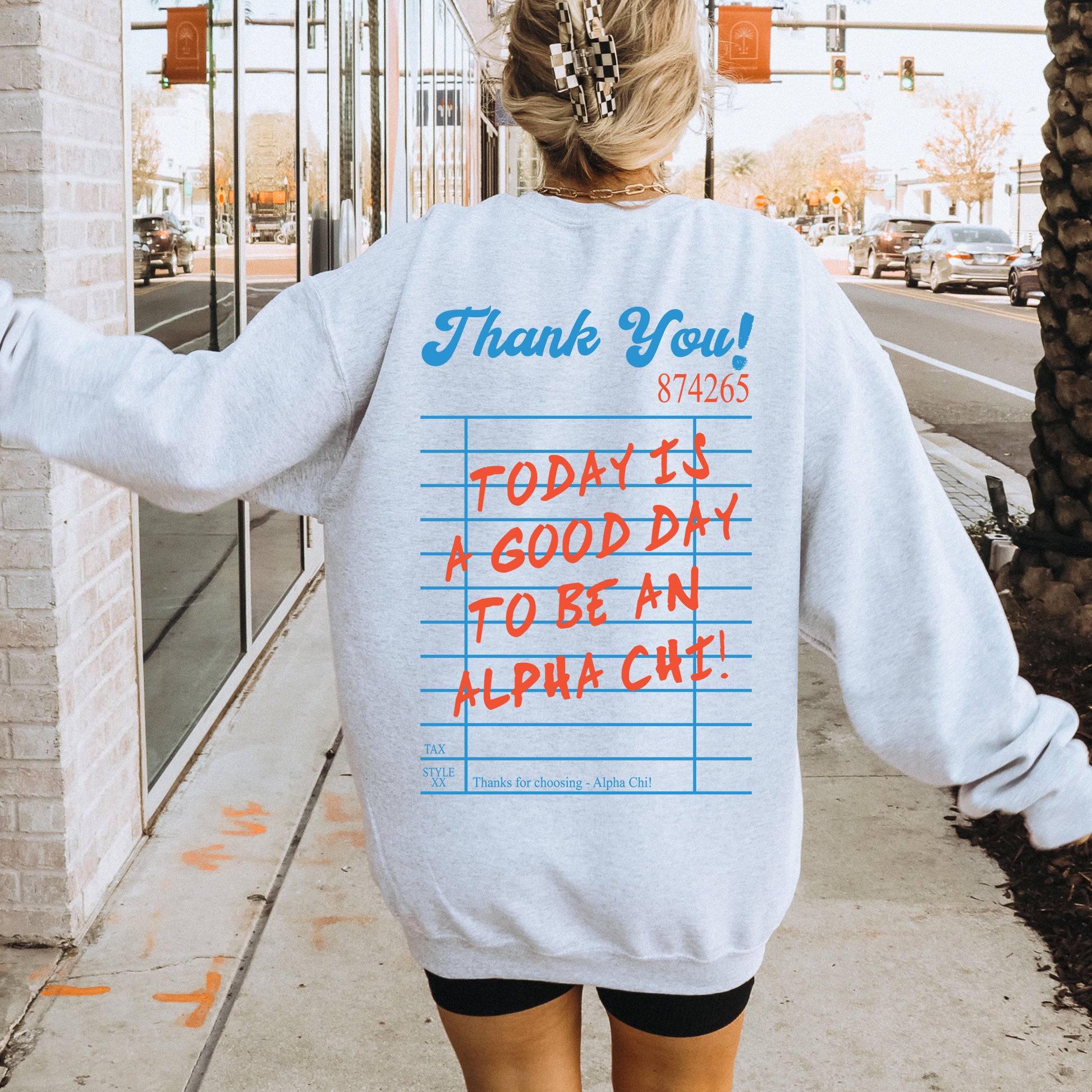 a woman walking down a sidewalk wearing a sweatshirt with writing on it