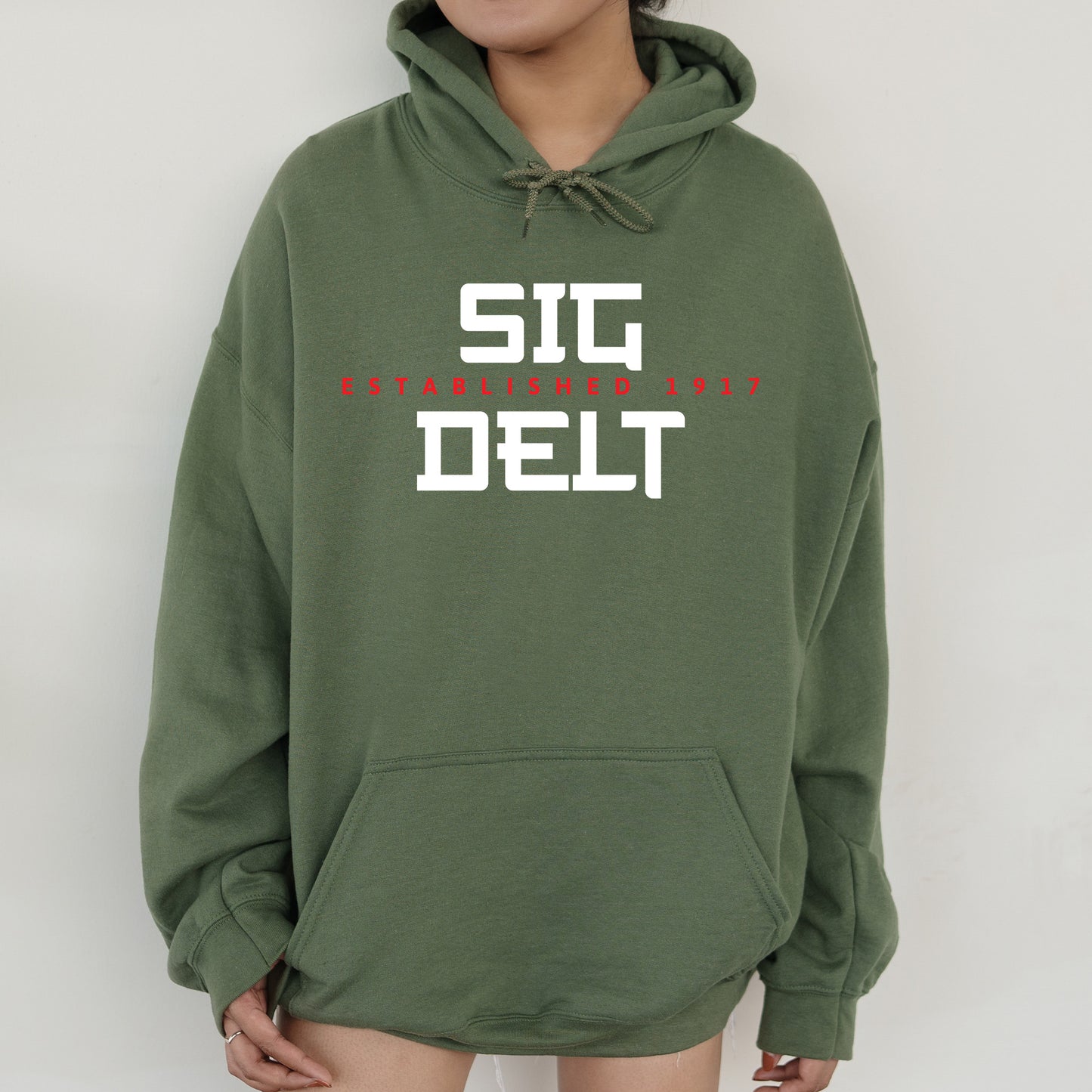 a woman wearing a green sweatshirt with the word sig delt printed on it