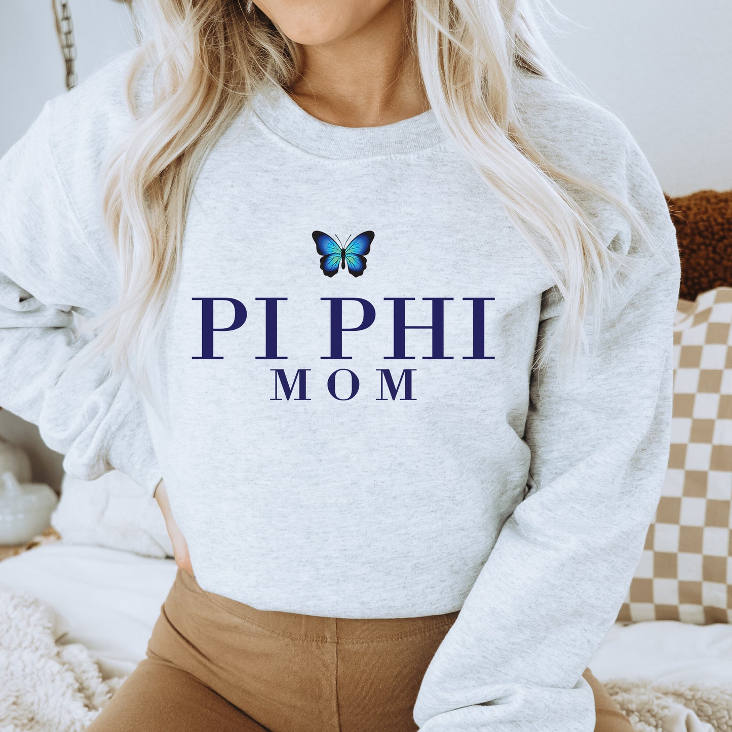 a woman wearing a sweatshirt that says pi phi mom