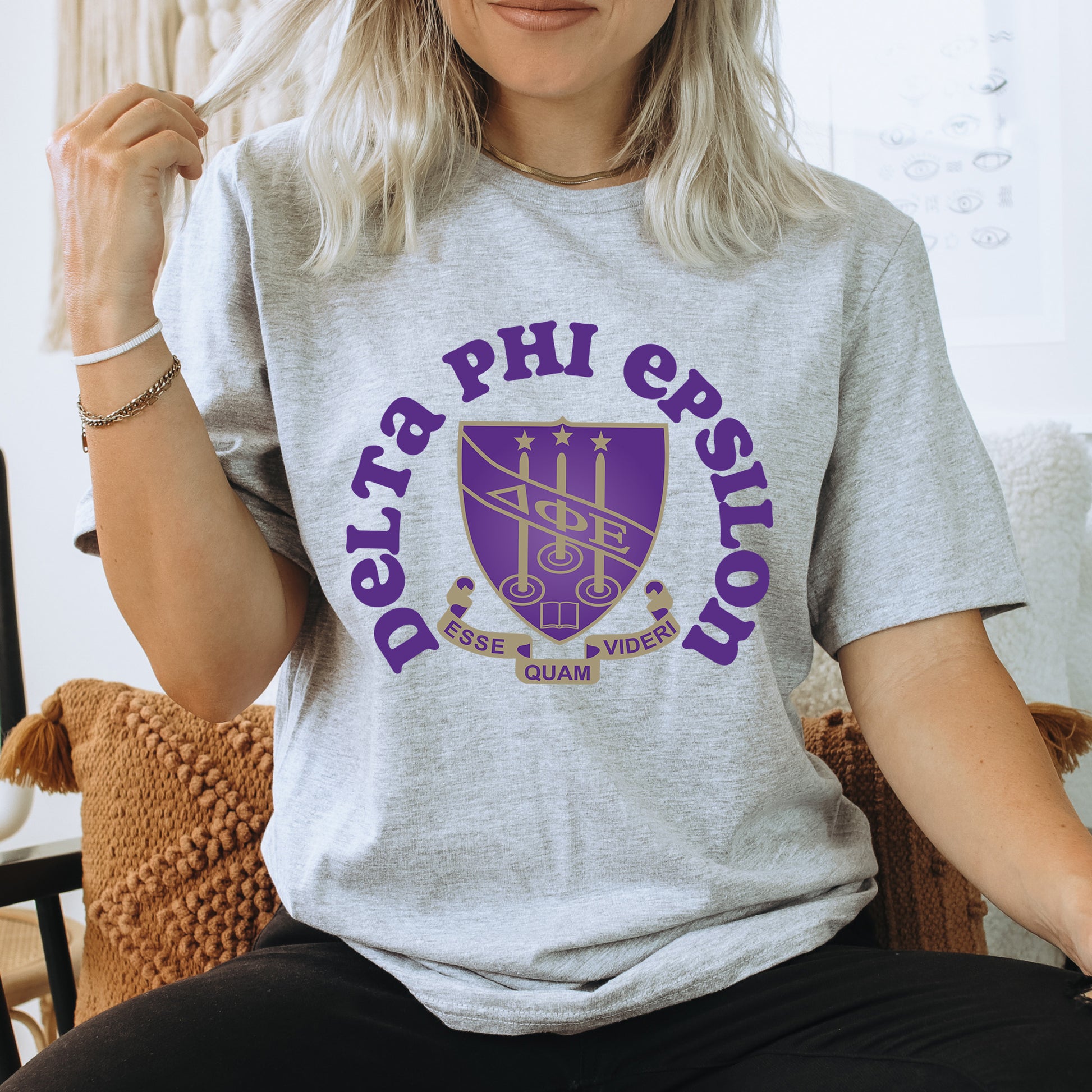 a woman sitting on a chair wearing a phi phi shirt