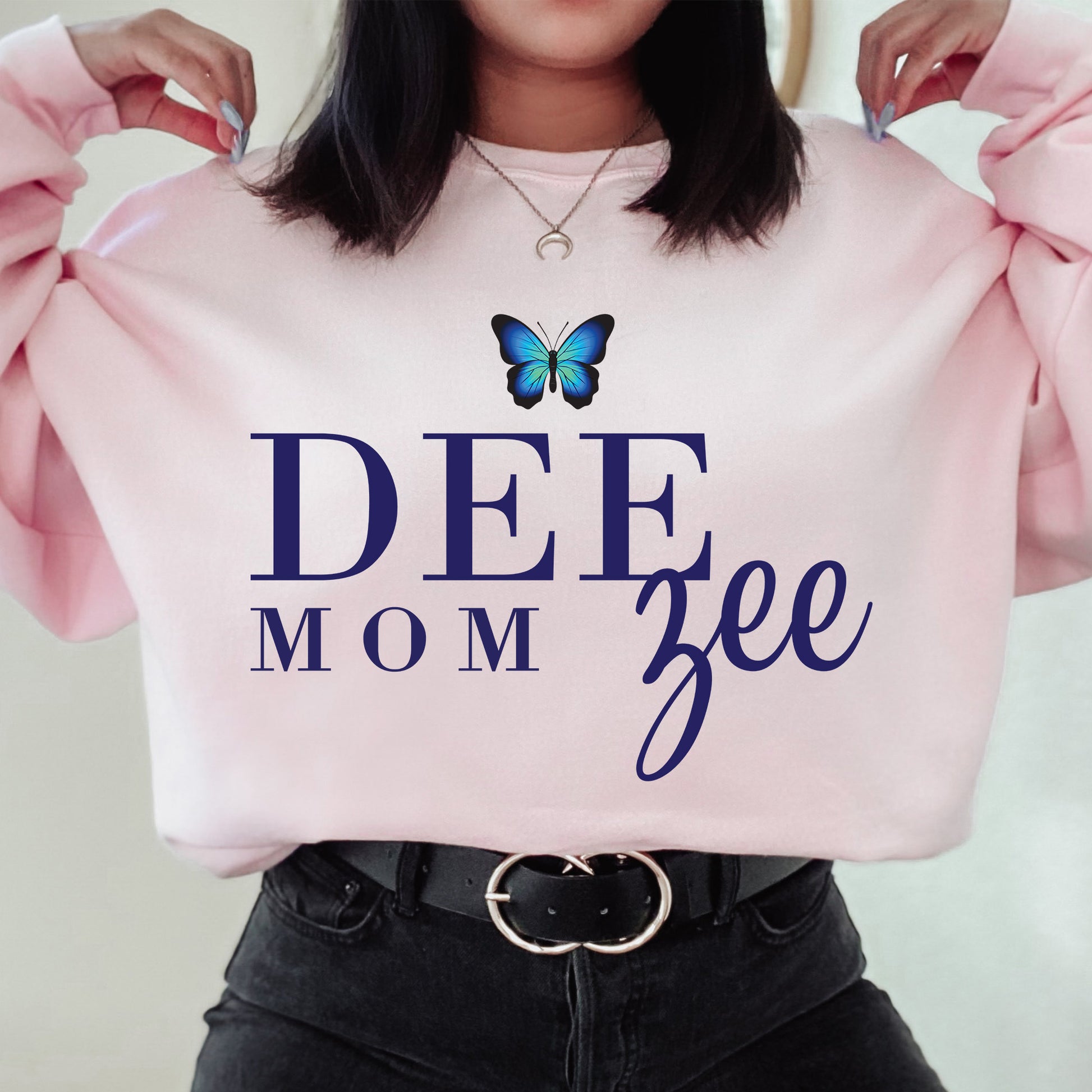 a woman holding a pink sweatshirt with a butterfly on it