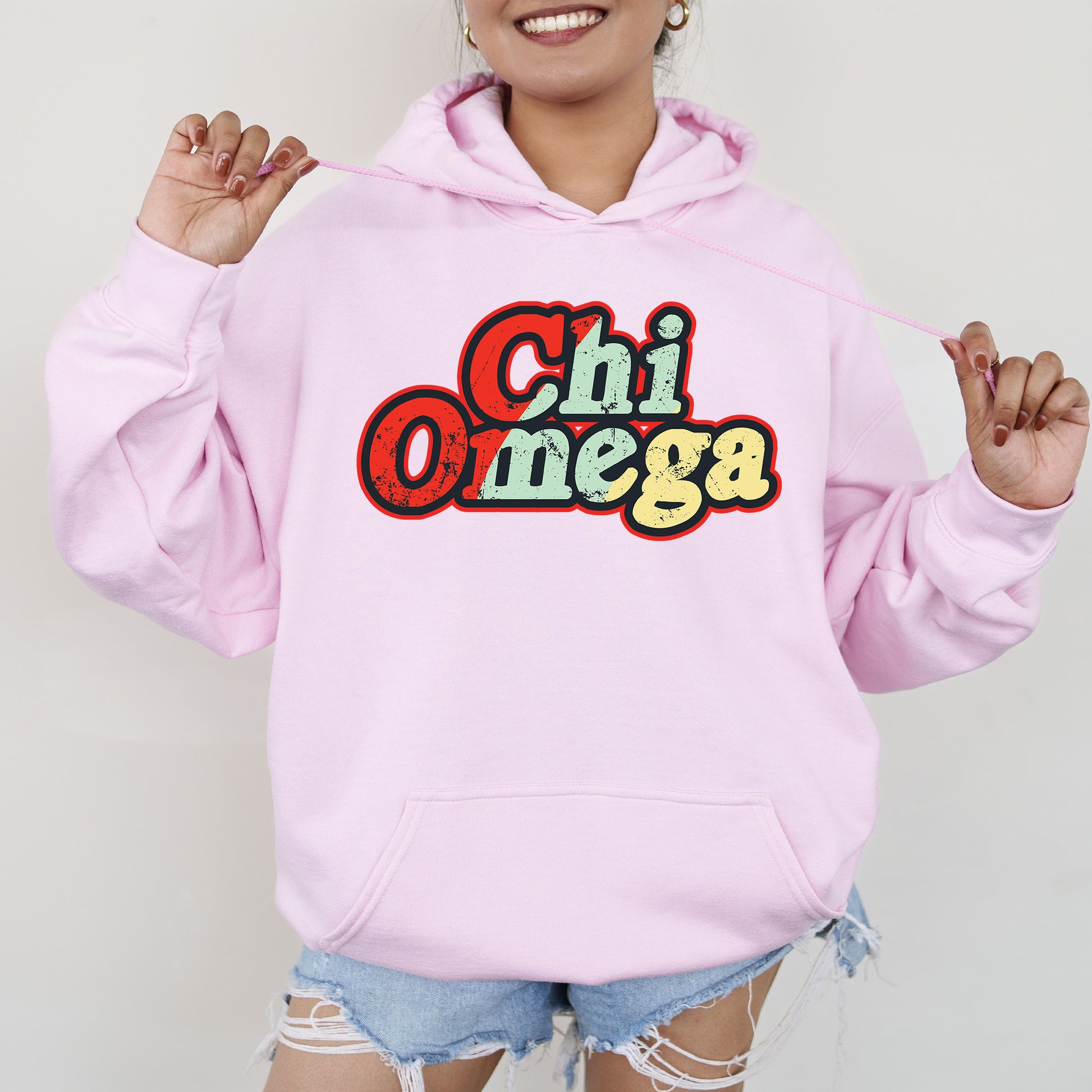 a woman wearing a pink hoodie that says chi omega