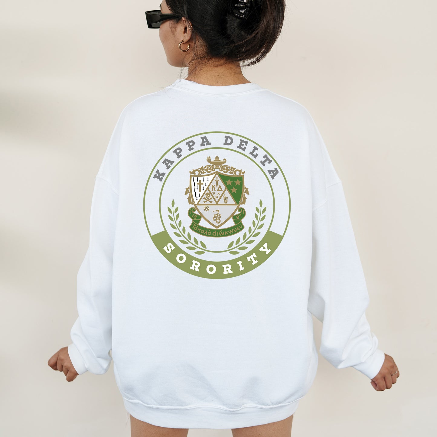 a woman wearing a white sweatshirt with a green and white crest