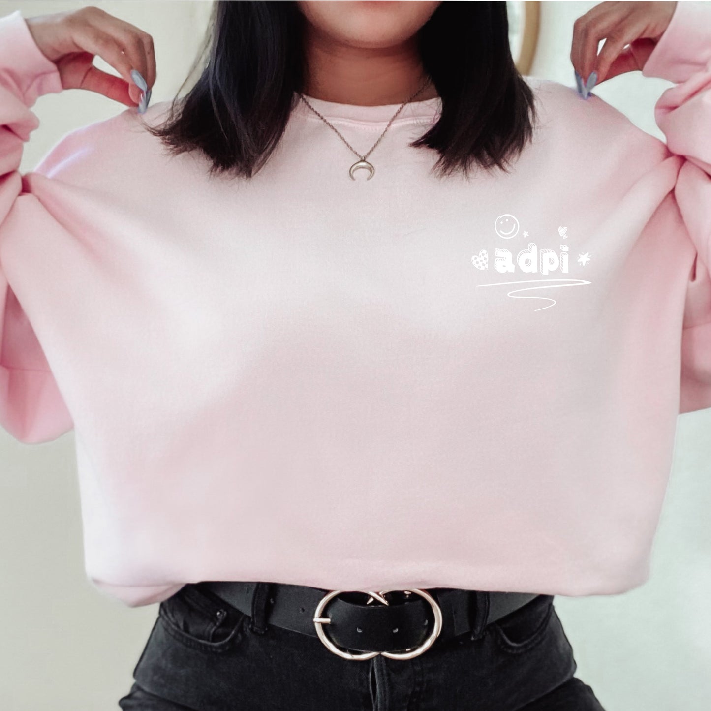 a woman is wearing a pink sweatshirt with a slogan on it