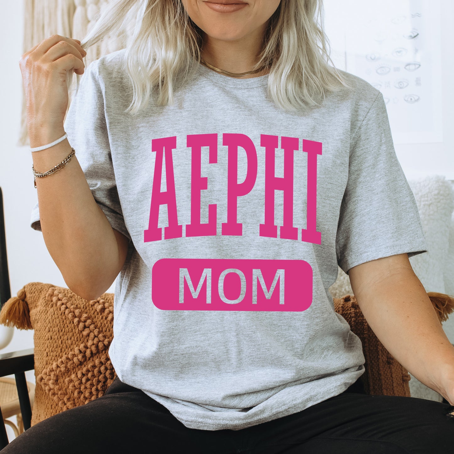 a woman sitting on a couch wearing a shirt that says aephi mom