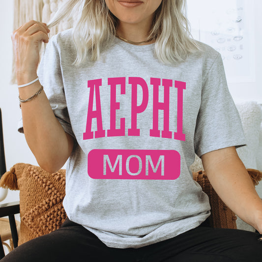 a woman sitting on a couch wearing a shirt that says aephi mom