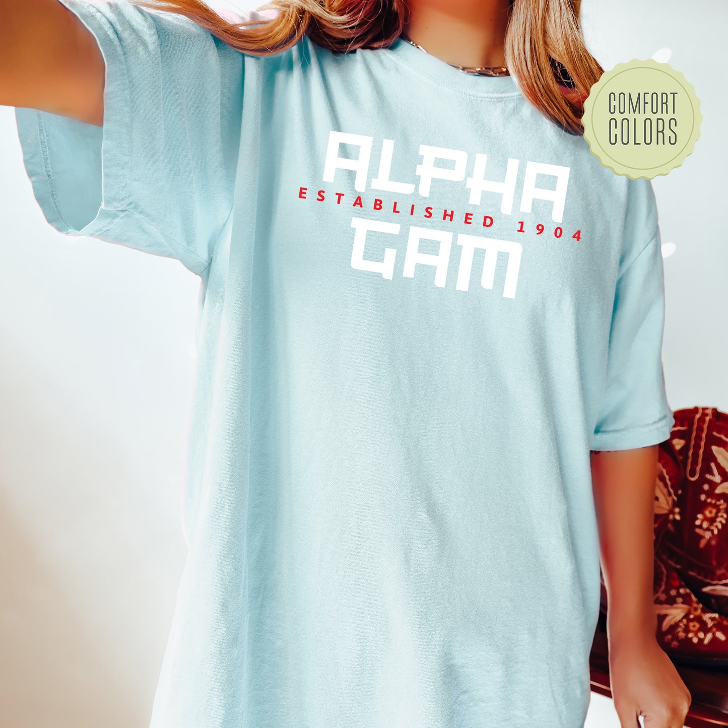 a woman wearing a light blue shirt that says alpha established 1950