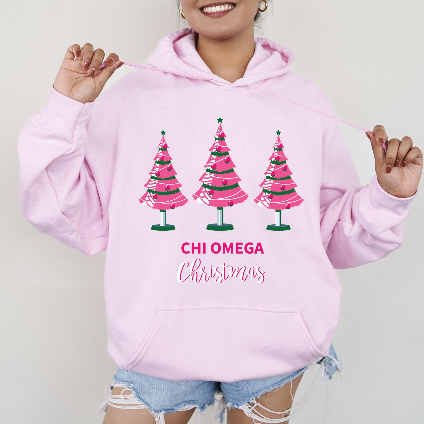 a woman wearing a pink hoodie with christmas trees on it