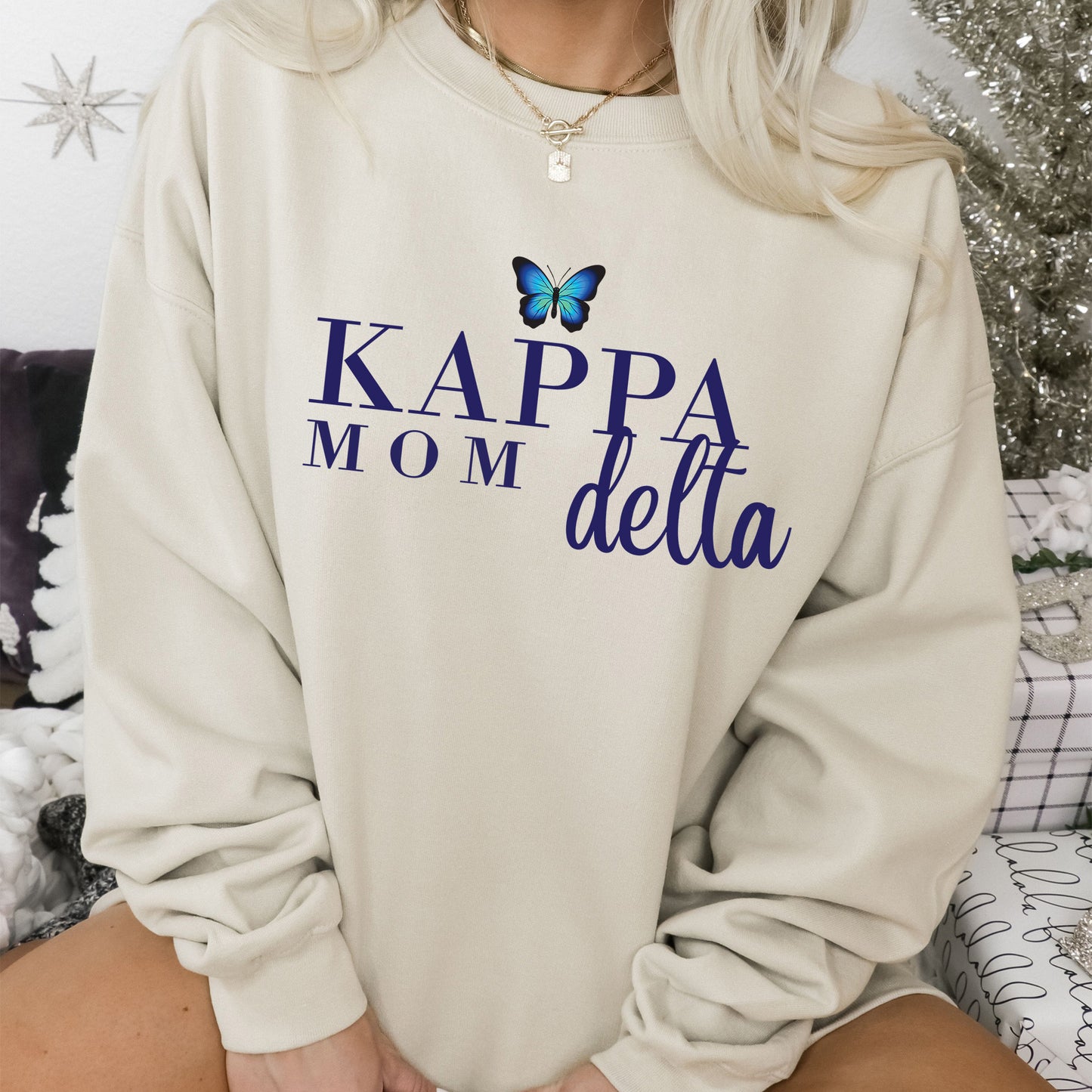 a woman wearing a sweatshirt that says kapa mom delta