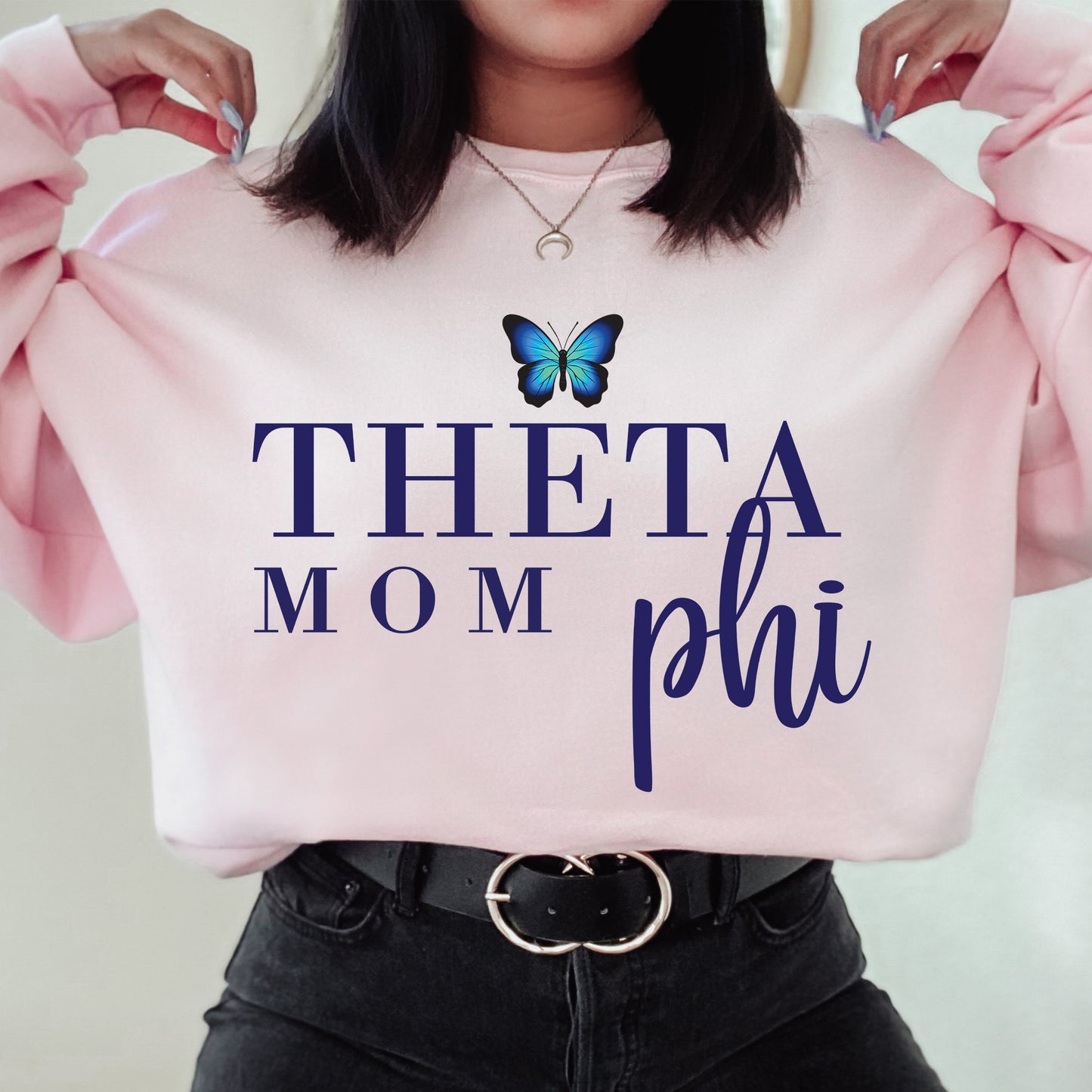 a woman holding a pink sweatshirt with a butterfly on it