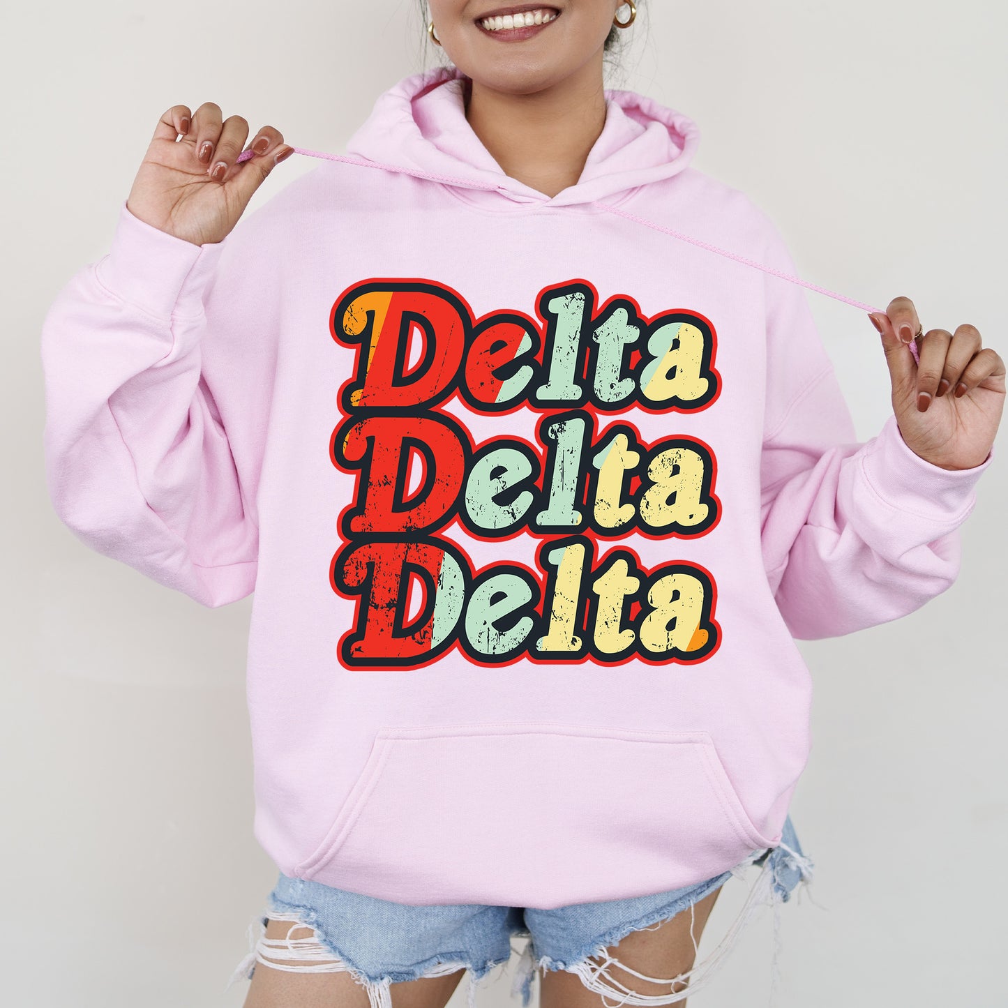 a woman wearing a pink hoodie that says delta delta