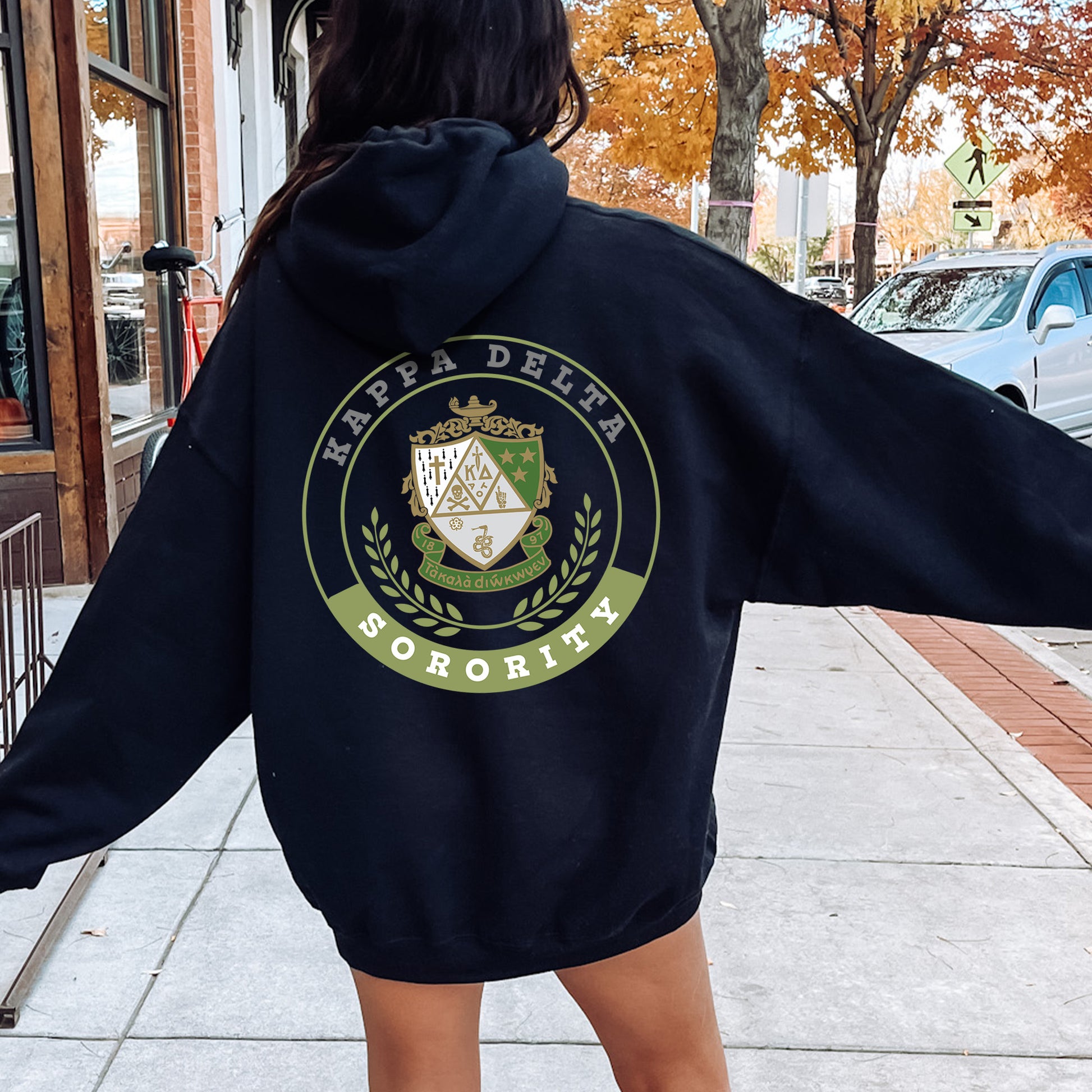 a woman walking down a sidewalk wearing a black hoodie