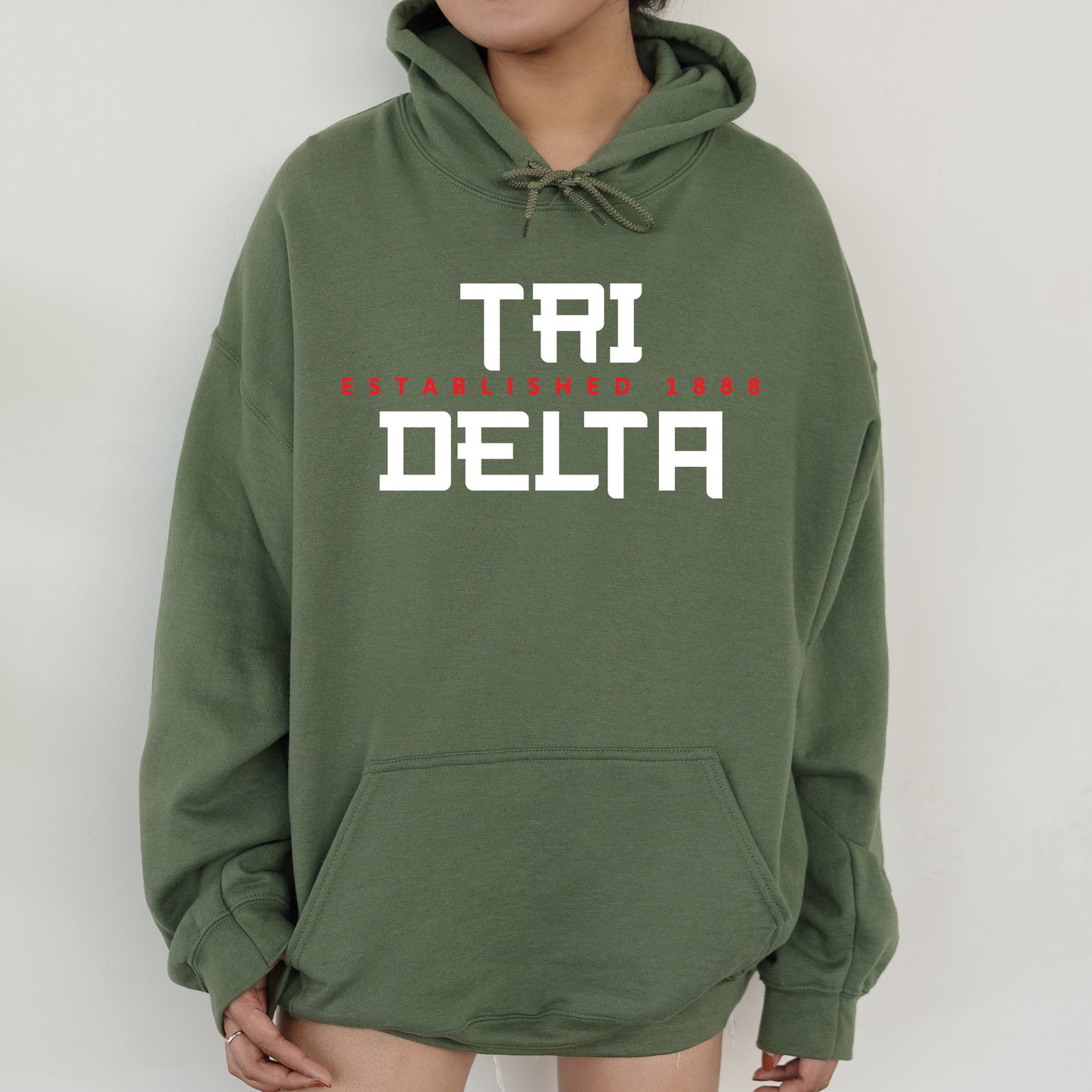 a woman wearing a green sweatshirt with the words tri delta printed on it