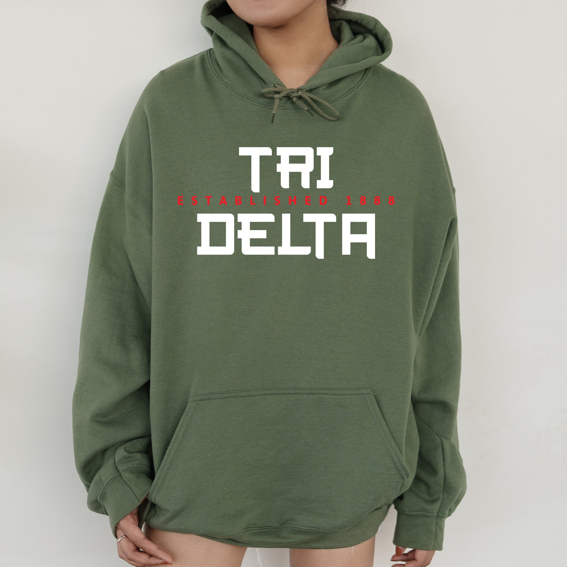 a woman wearing a green sweatshirt with the words tri delta printed on it