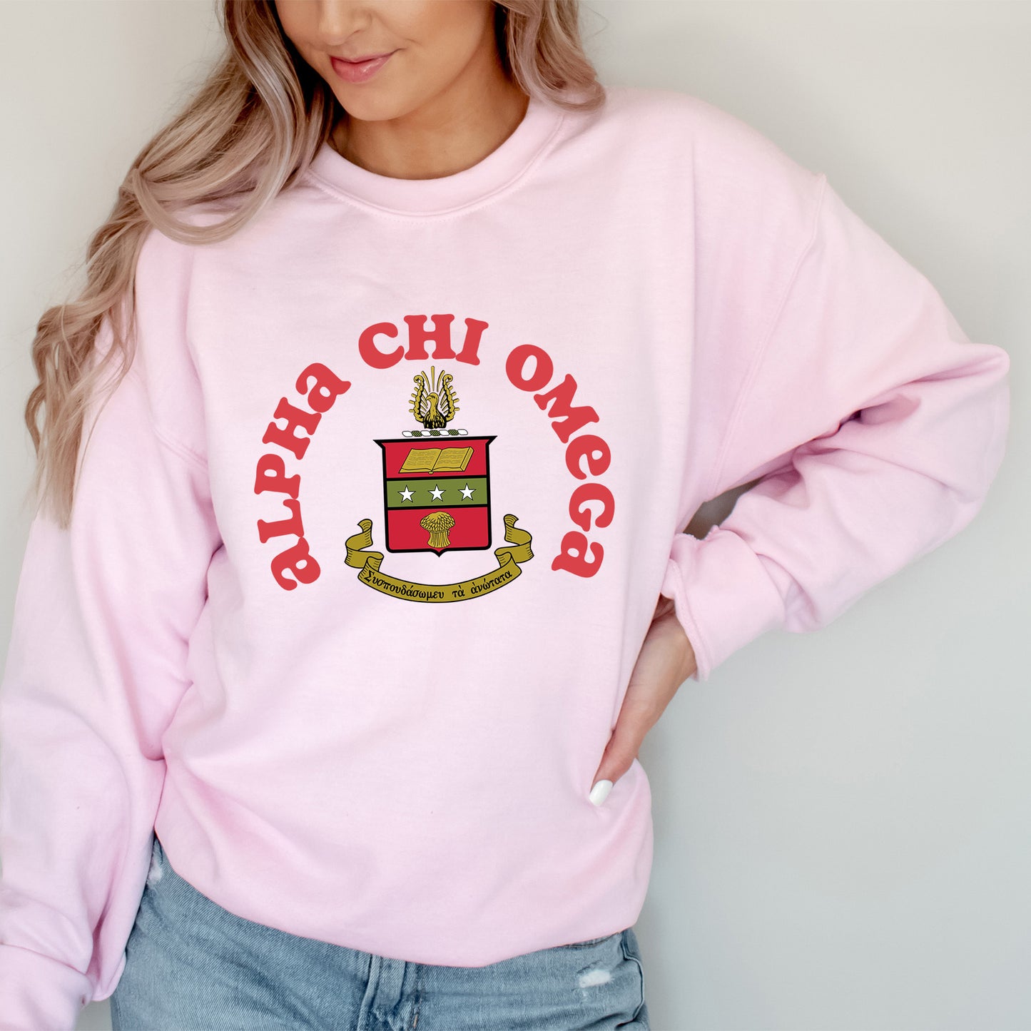 a woman wearing a pink sweatshirt with a crest on it