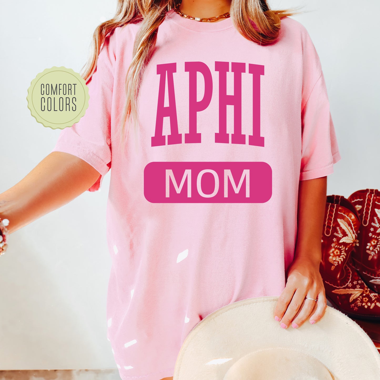 a woman wearing a pink shirt that says aphi mom