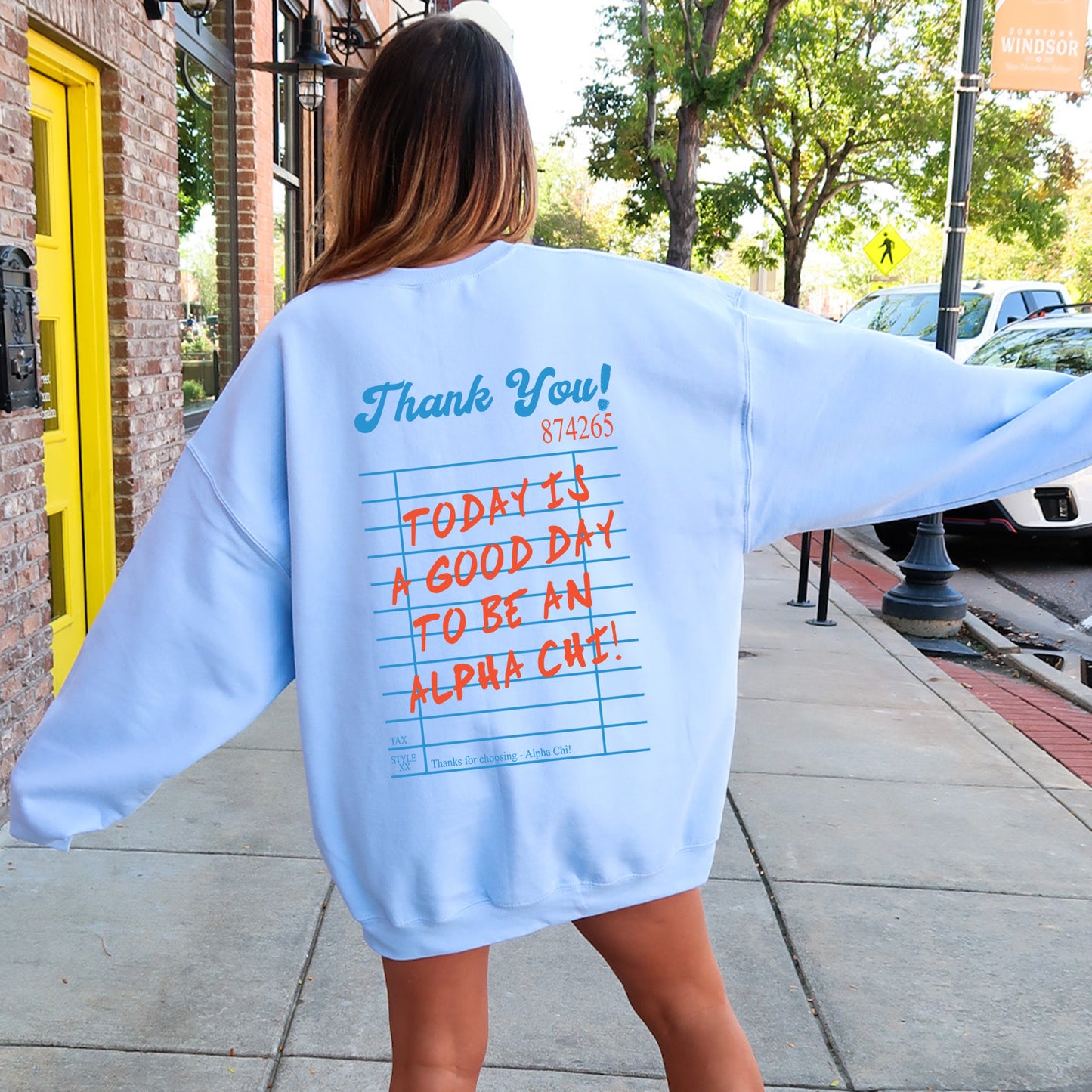 a woman walking down a sidewalk wearing a blue sweatshirt