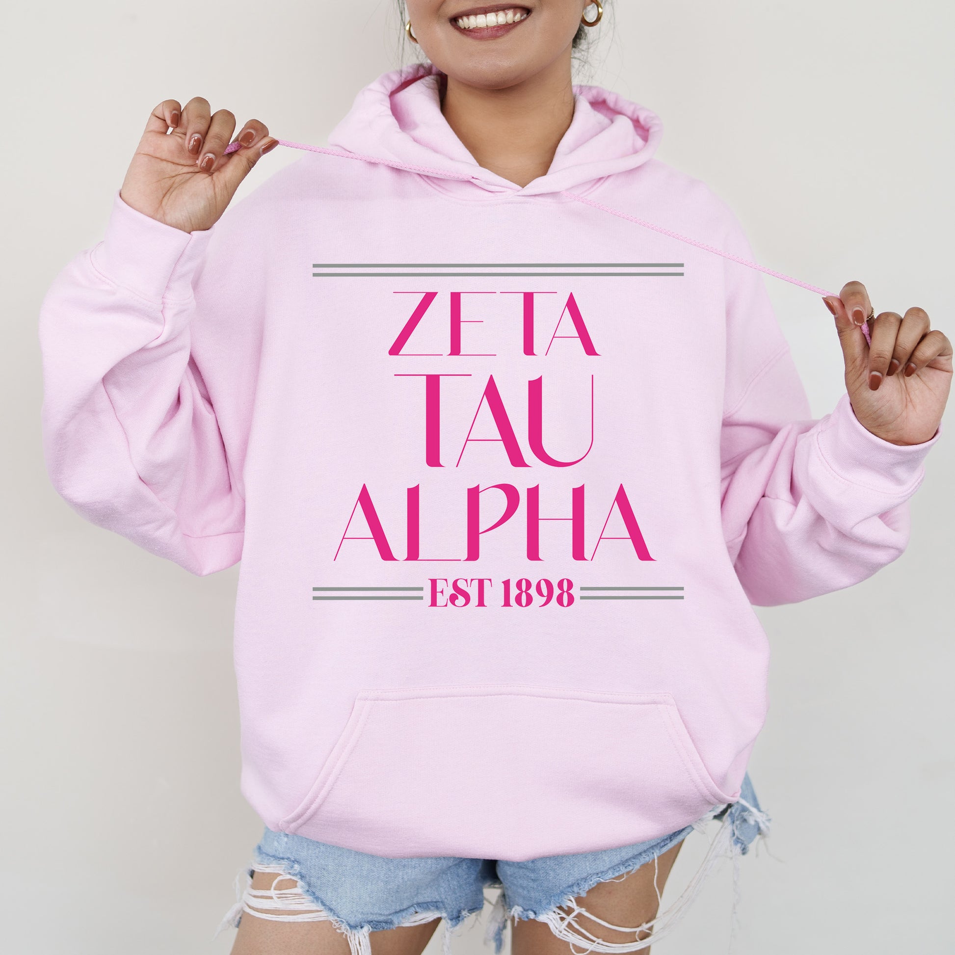 a woman wearing a pink hoodie that says zeia tau alpha
