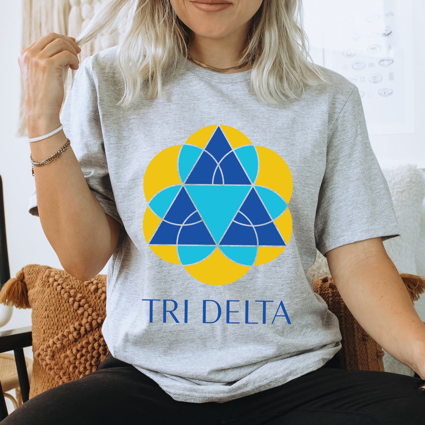 a woman sitting on a chair wearing a tri delta shirt