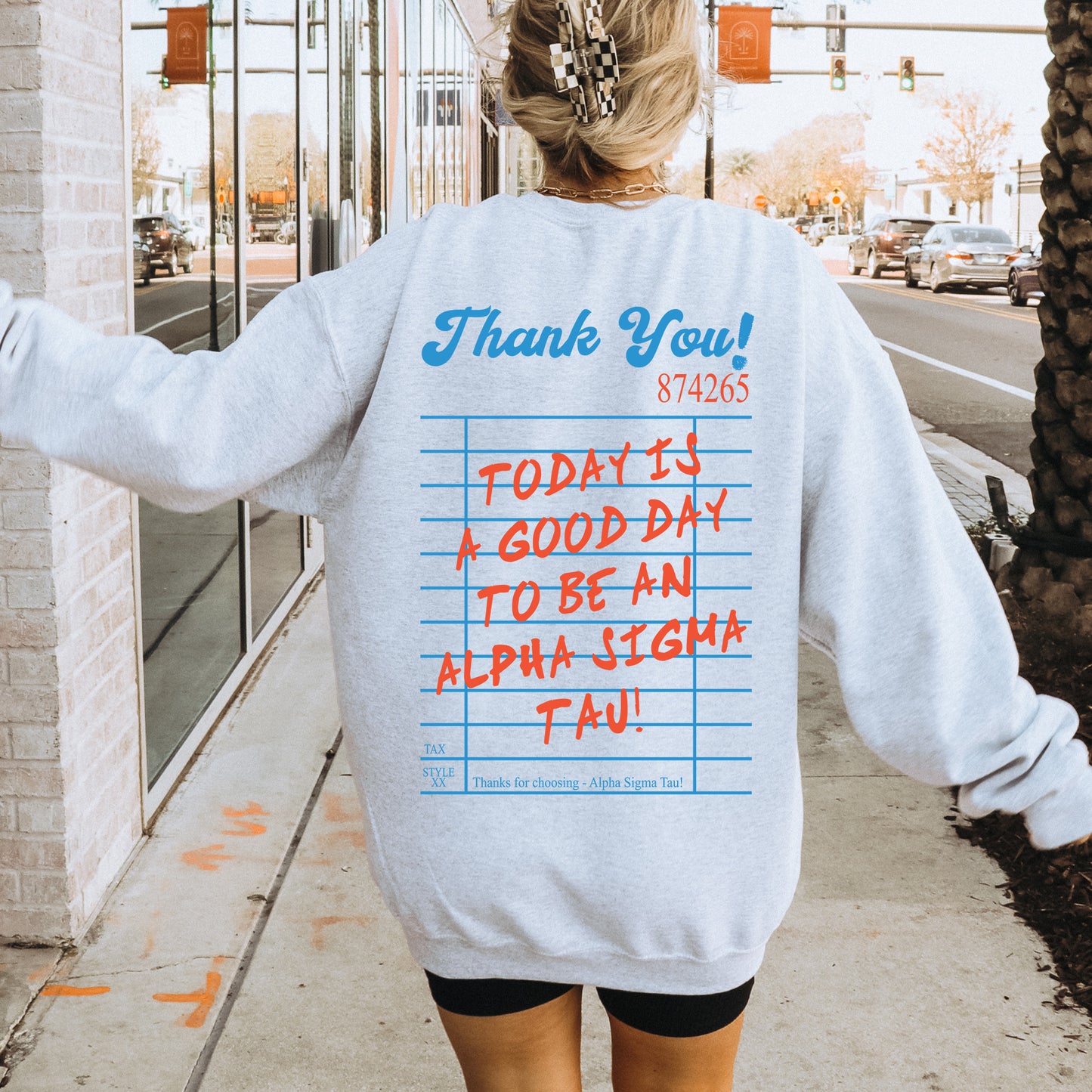 a woman walking down a sidewalk wearing a sweatshirt with writing on it