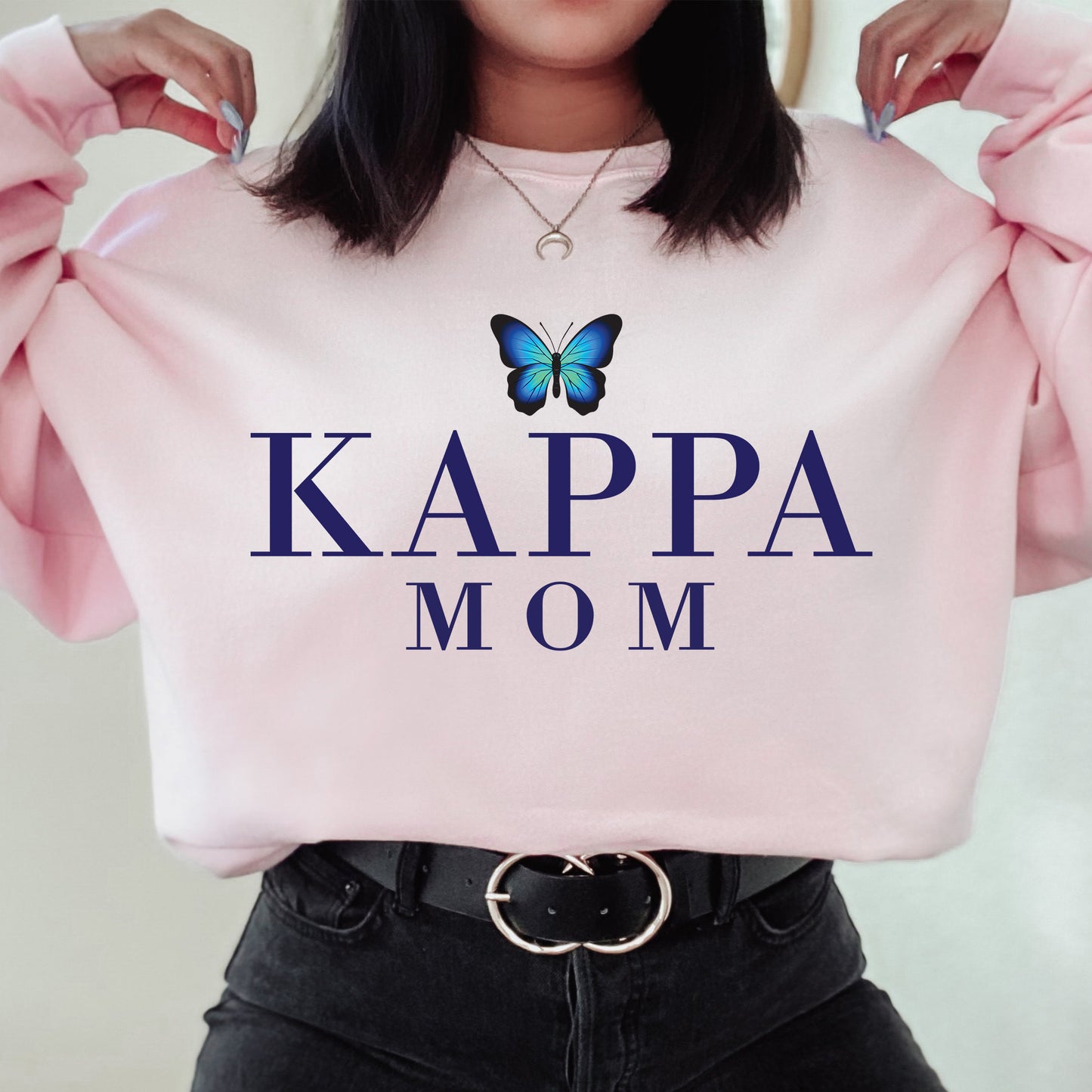 a woman holding a pink sweatshirt with a butterfly on it