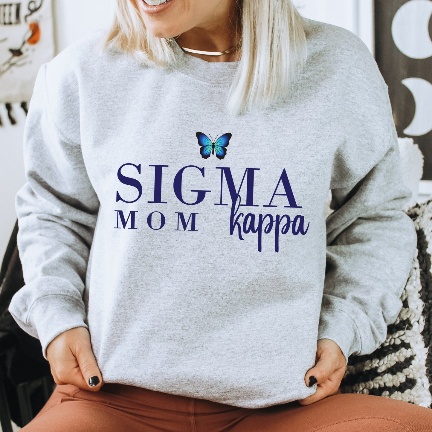 a woman sitting on a chair with a butterfly on her sweatshirt