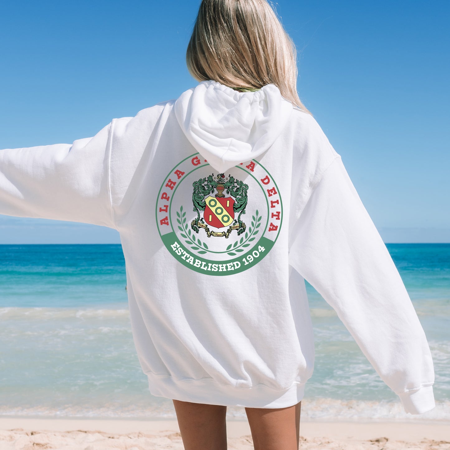 a woman standing on a beach wearing a white hoodie