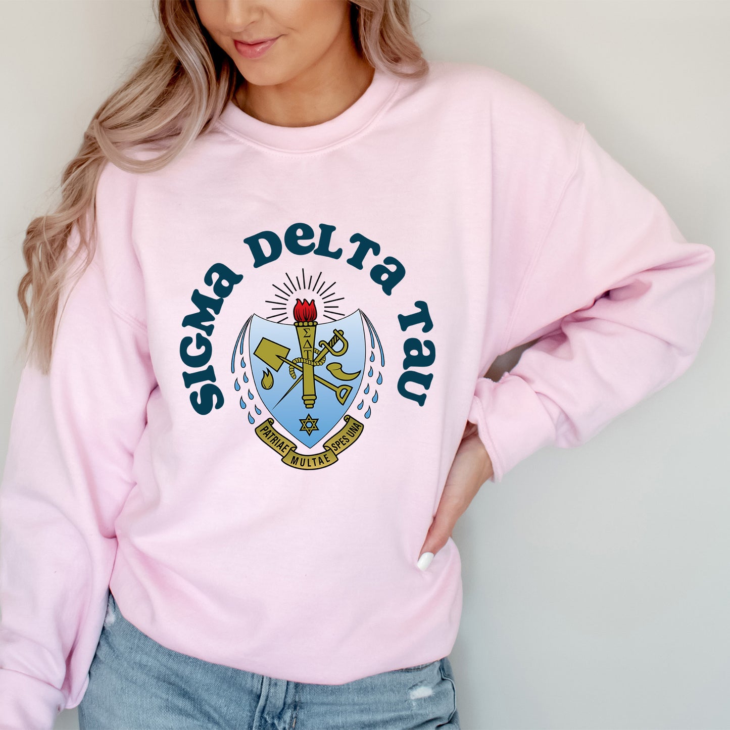 a woman wearing a pink sweatshirt with a crest on it