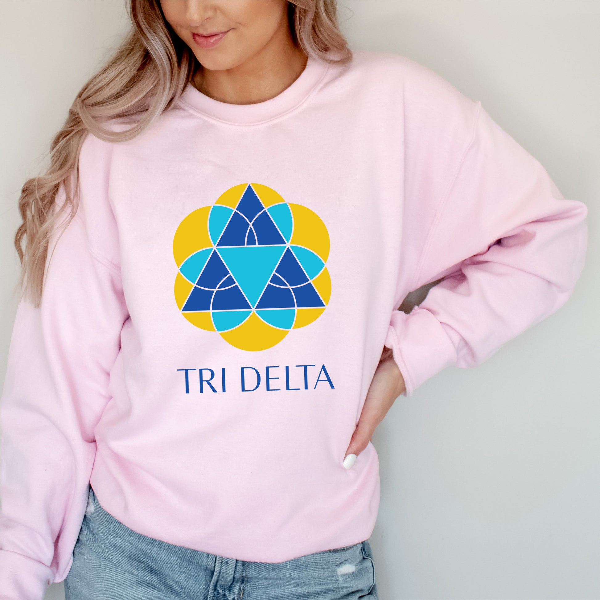 a woman wearing a pink sweatshirt with the tri delta logo on it