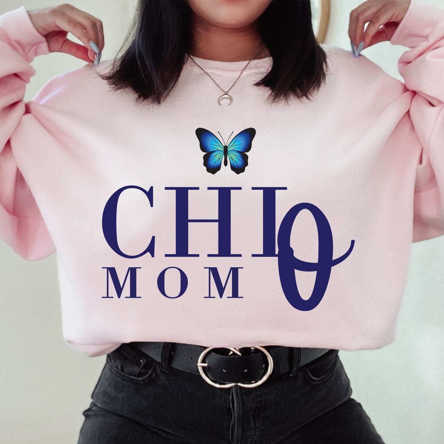 a woman holding a pink sweatshirt with a butterfly on it