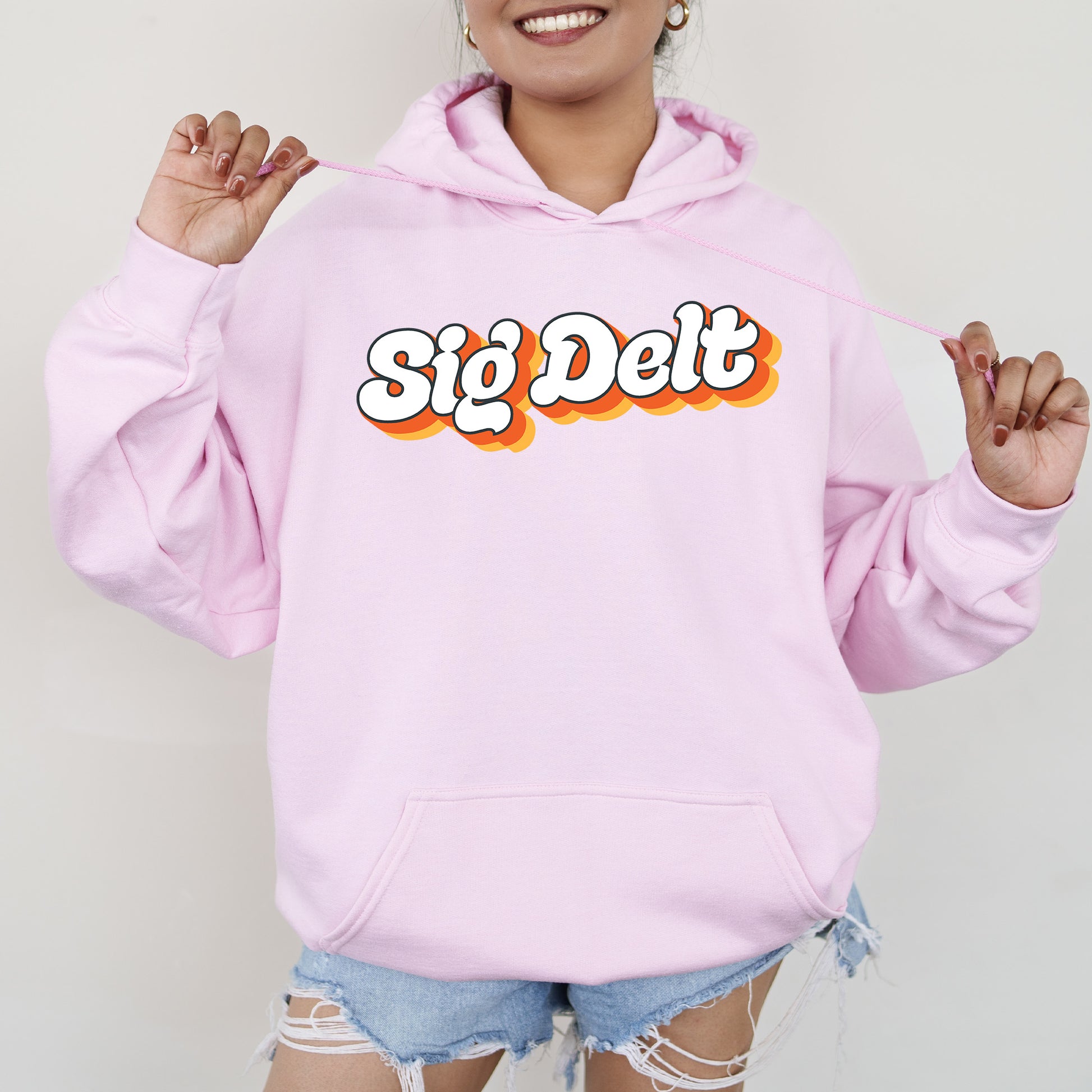 a woman wearing a pink hoodie with the word sig det on it