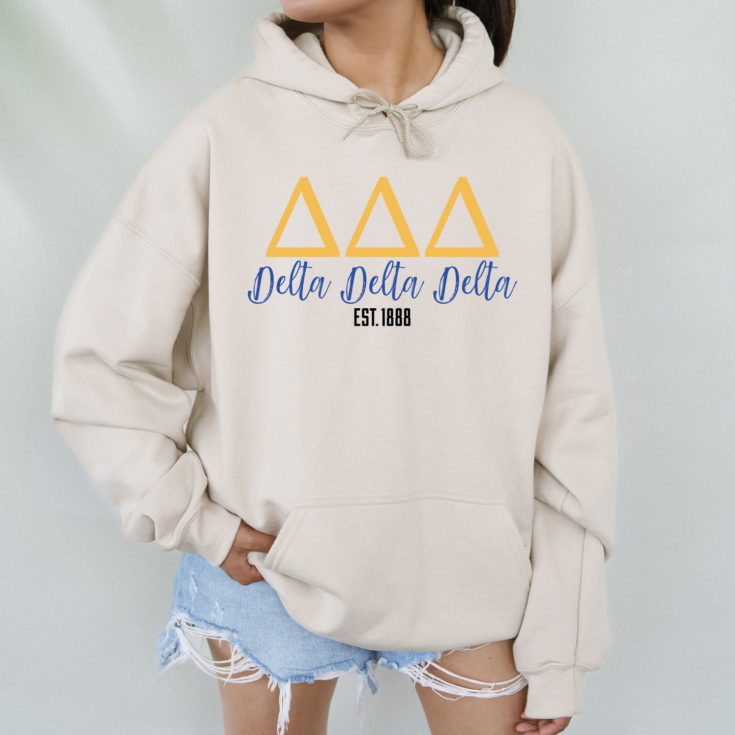 a woman wearing a sweatshirt with the delta delta delta on it
