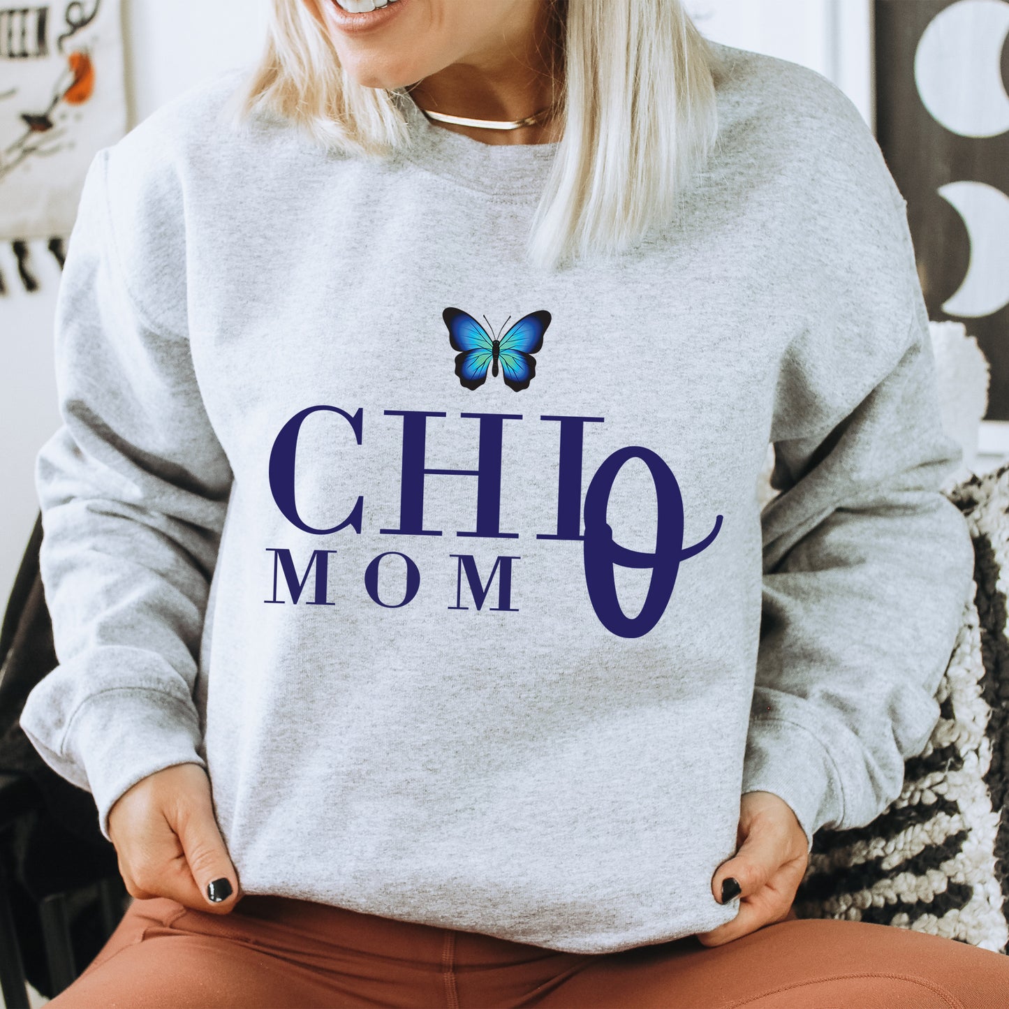 a woman sitting on a chair wearing a sweatshirt with a butterfly on it