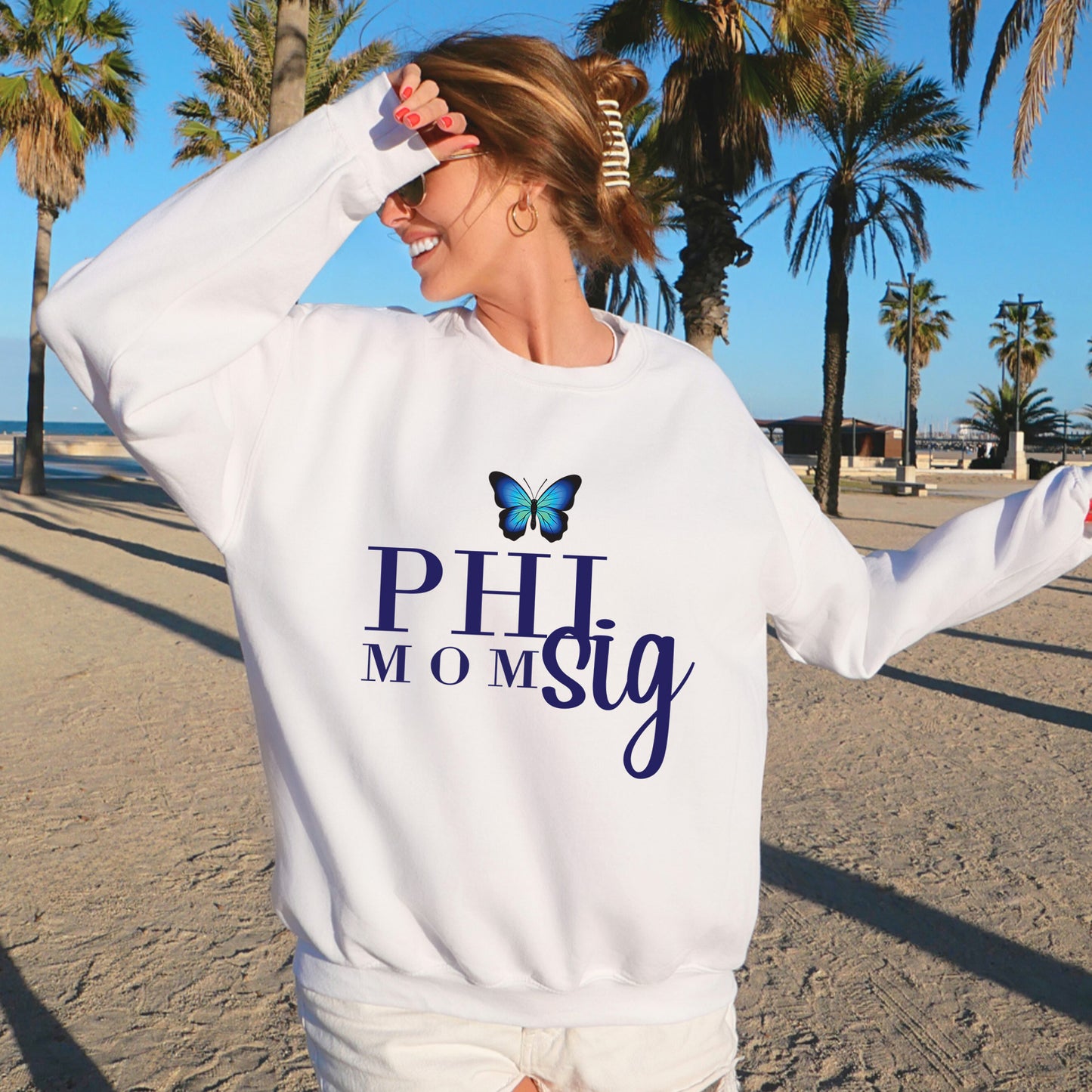a woman standing on a beach wearing a white sweatshirt