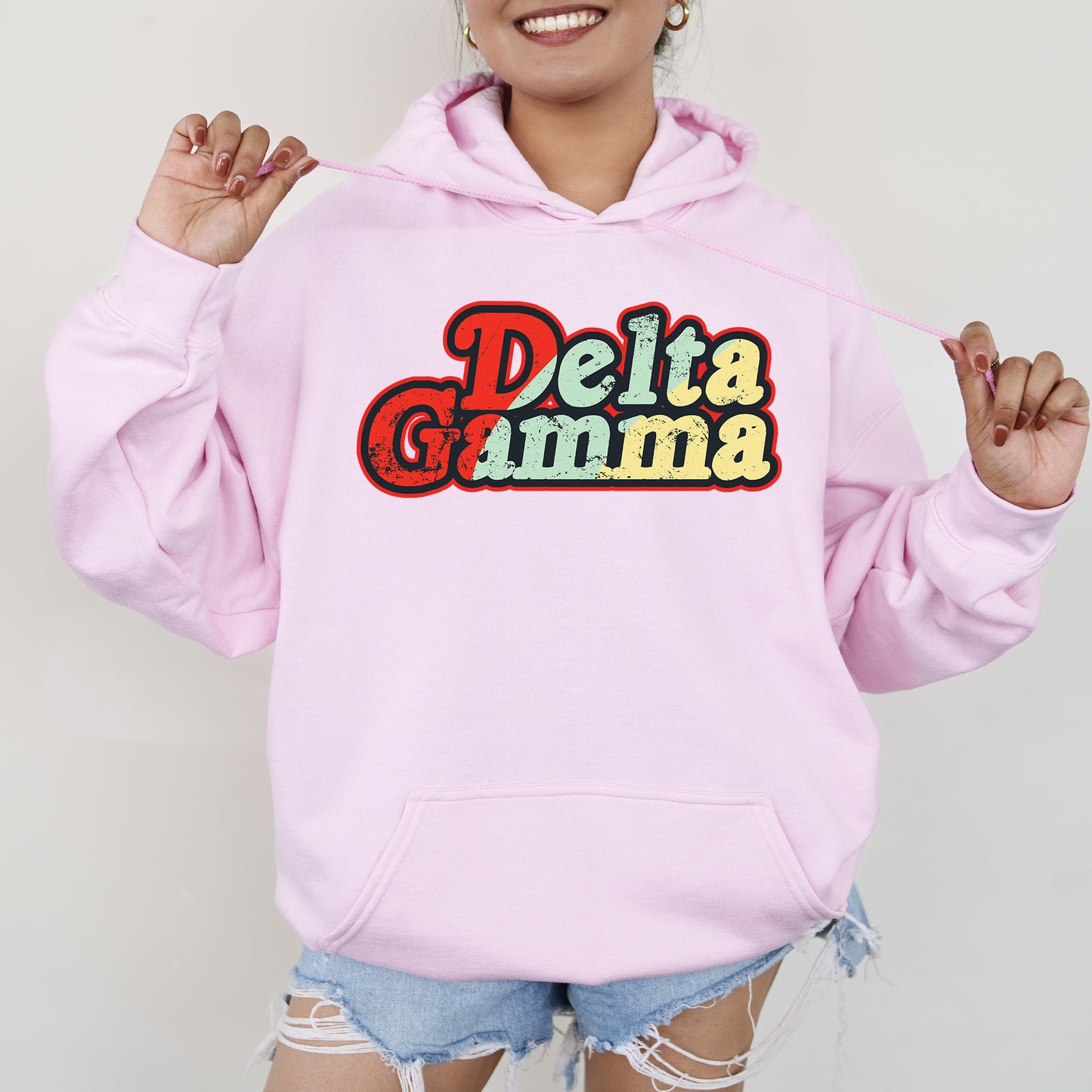 a woman wearing a pink hoodie with the word delta gumma on it