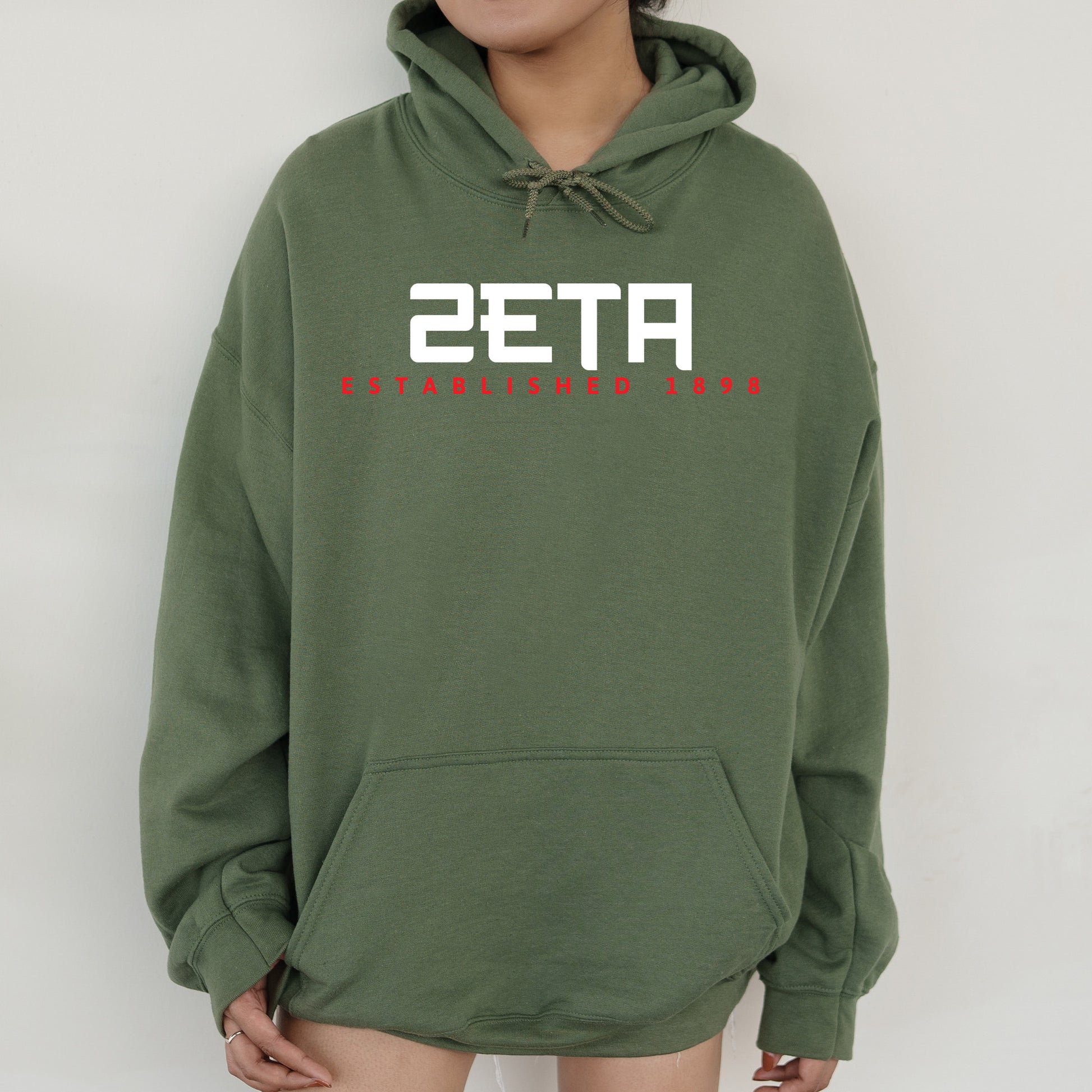 a person wearing a green sweatshirt with a red and white design on it