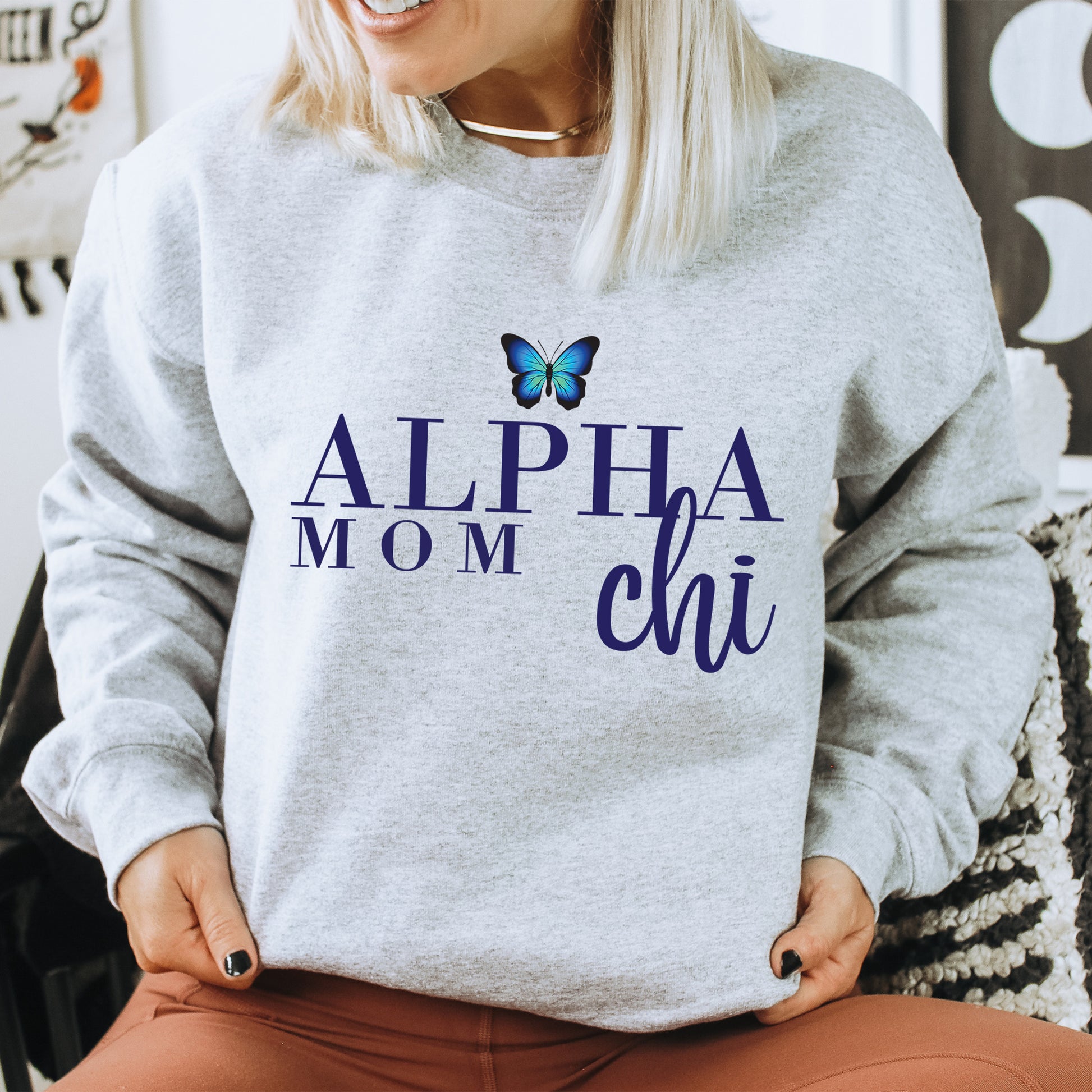 a woman sitting on a chair with a butterfly on her sweatshirt