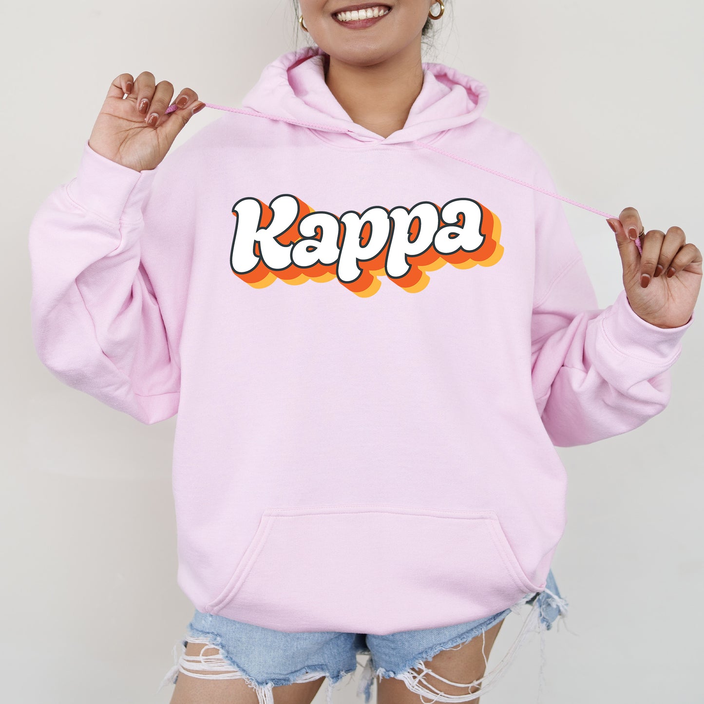 a woman wearing a pink hoodie with the word kappa on it